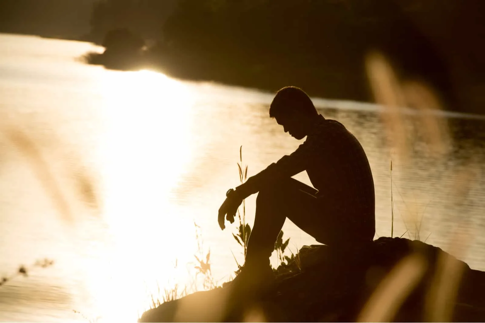 Sad young man at sunset by the river
