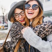 two smiling female friends hugging