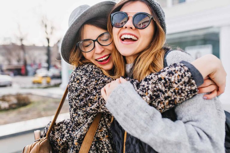 two smiling female friends hugging