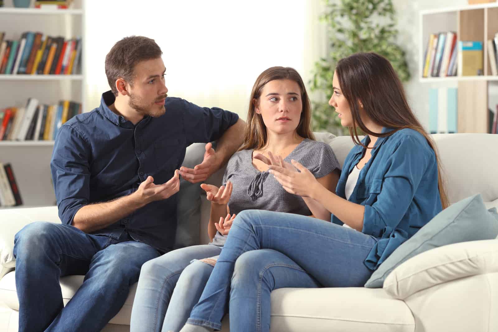 Tre amici seri che parlano seduti su un divano nel soggiorno di casa