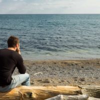 an imaginary man sits and looks at the sea