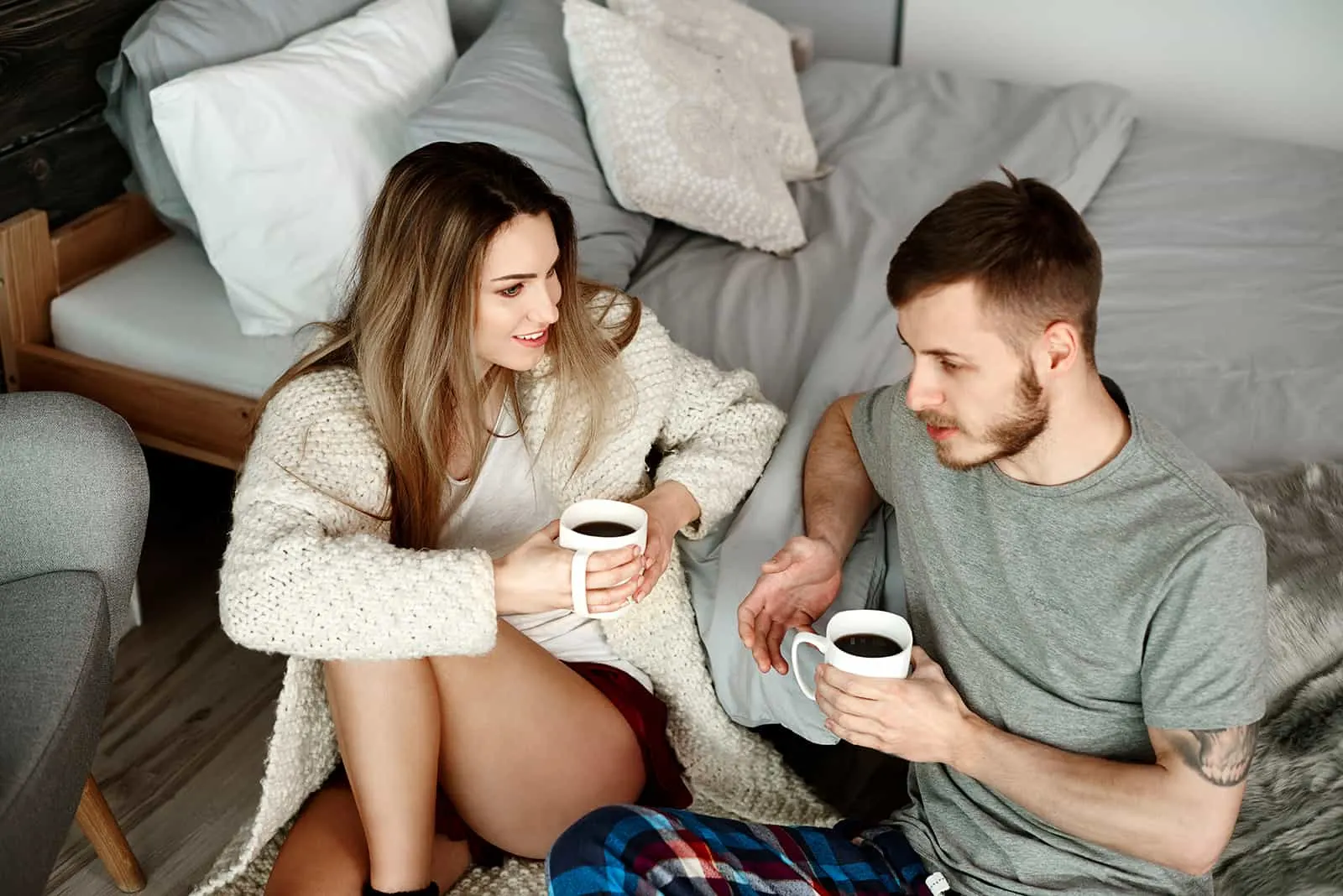 a couple having a conversation while drinking coffee in apartment