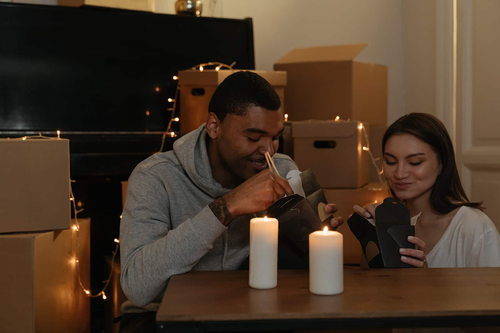 una coppia che trascorre una serata romantica con le candele in casa, mangiando cibo cinese