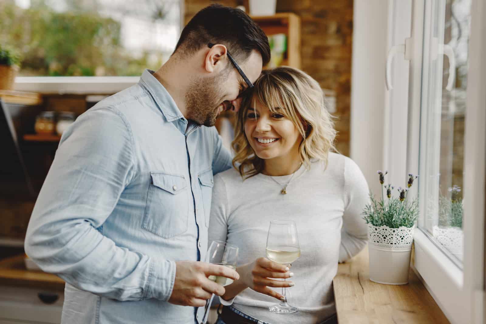 una pareja de enamorados ríe mientras sostienen copas de vino