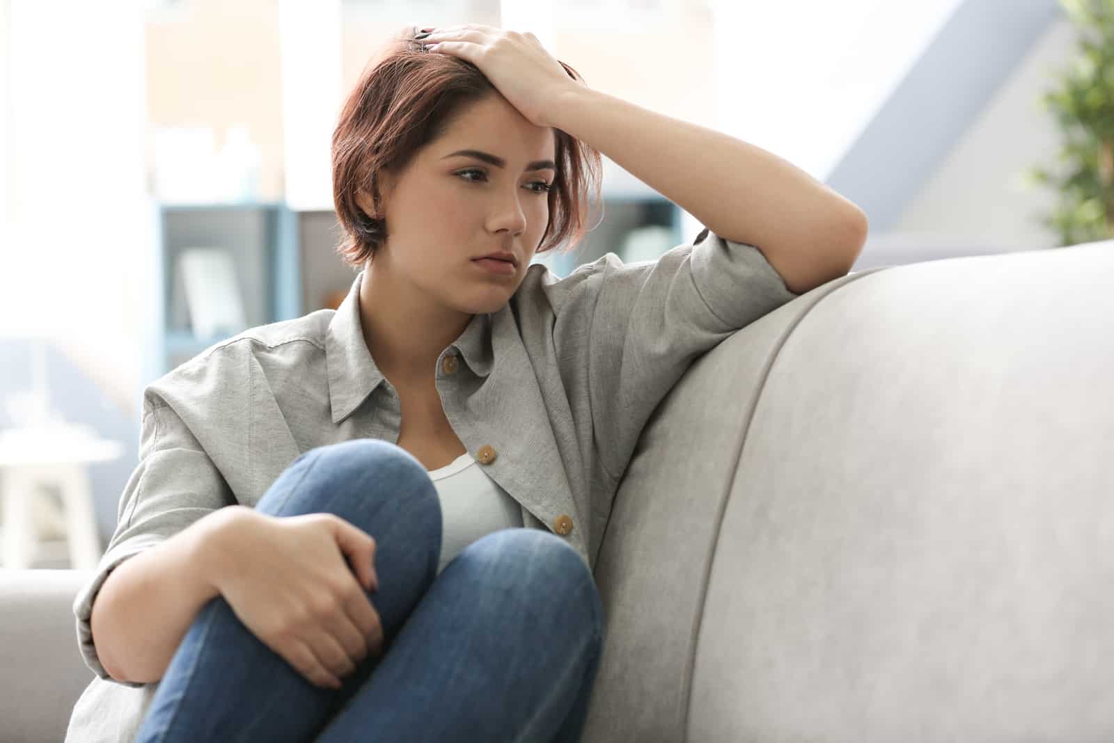 a depressed short-haired woman sitting on a sofa