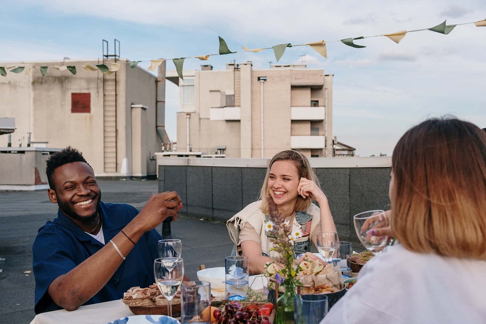 a group of friends having fun while sitting at the table at the party on the rooftop