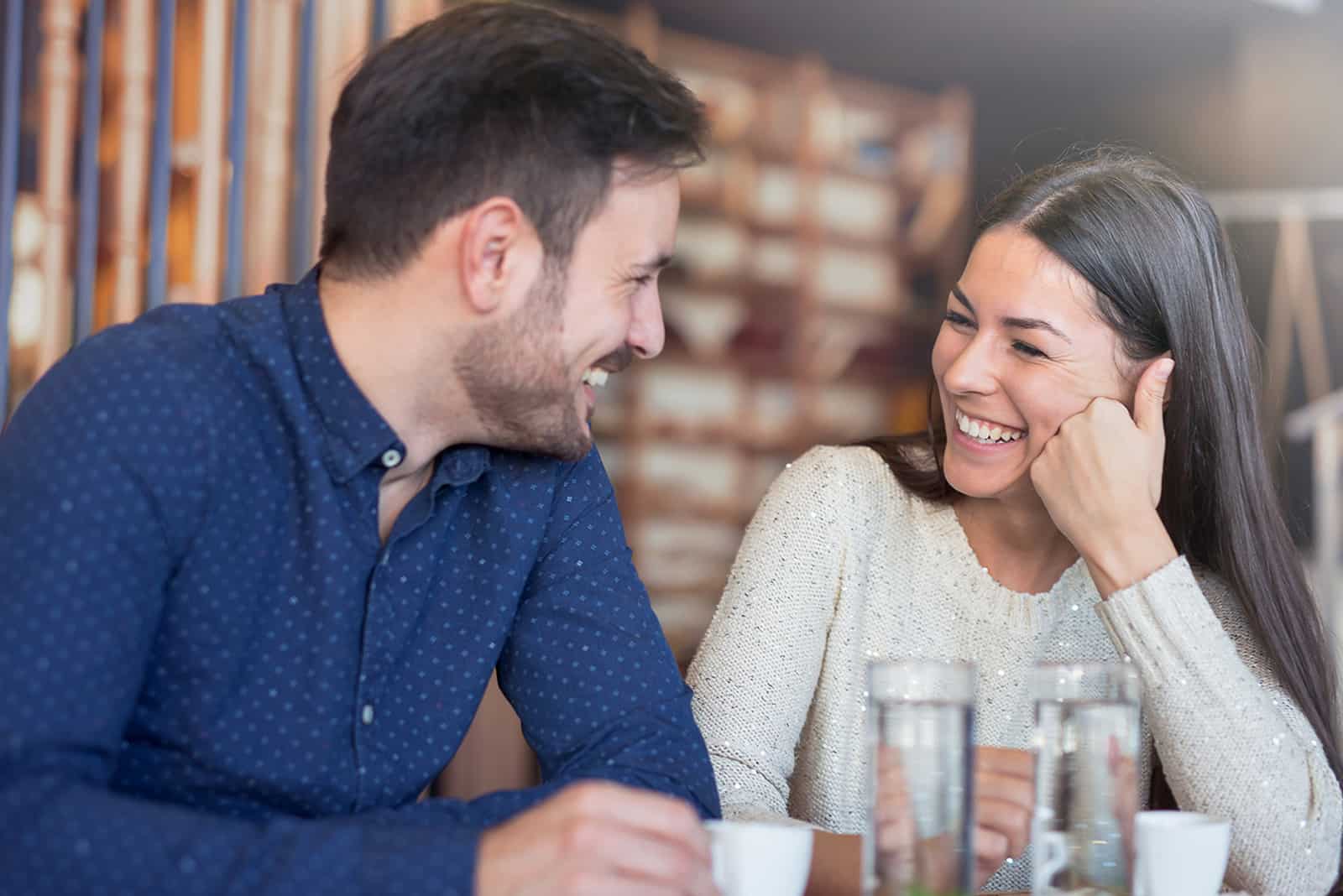 a laughing couple sitting in the cafe and enjoying conversation