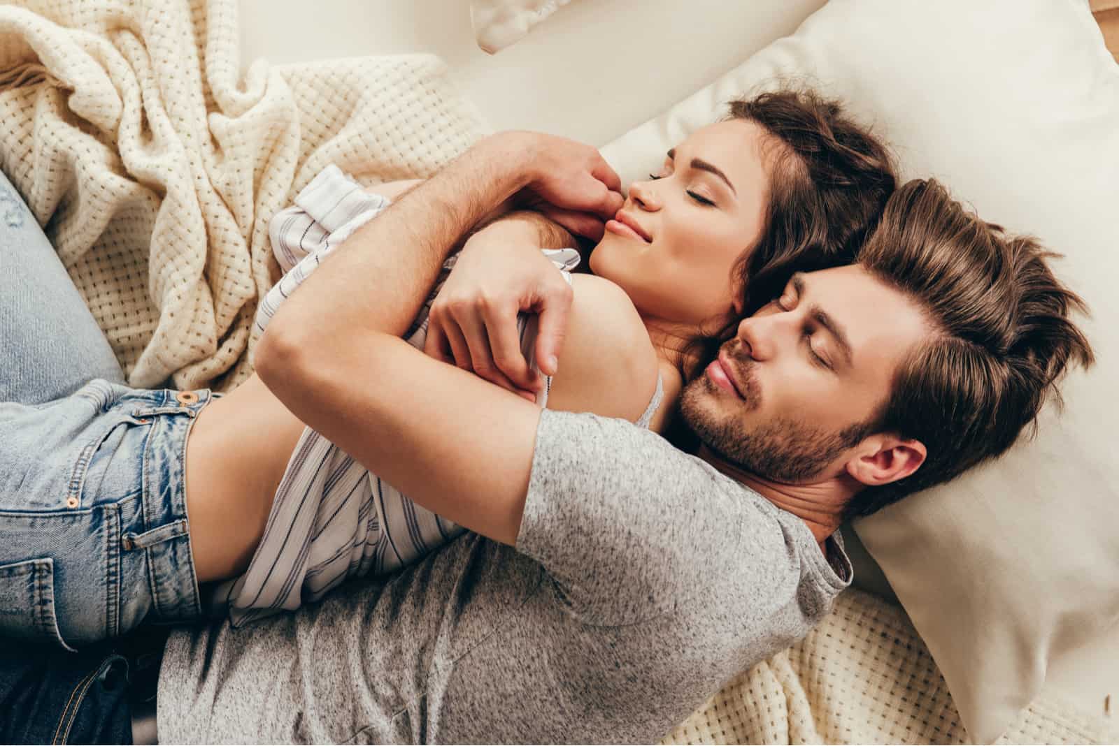 una pareja de enamorados abrazados y tumbados en la cama