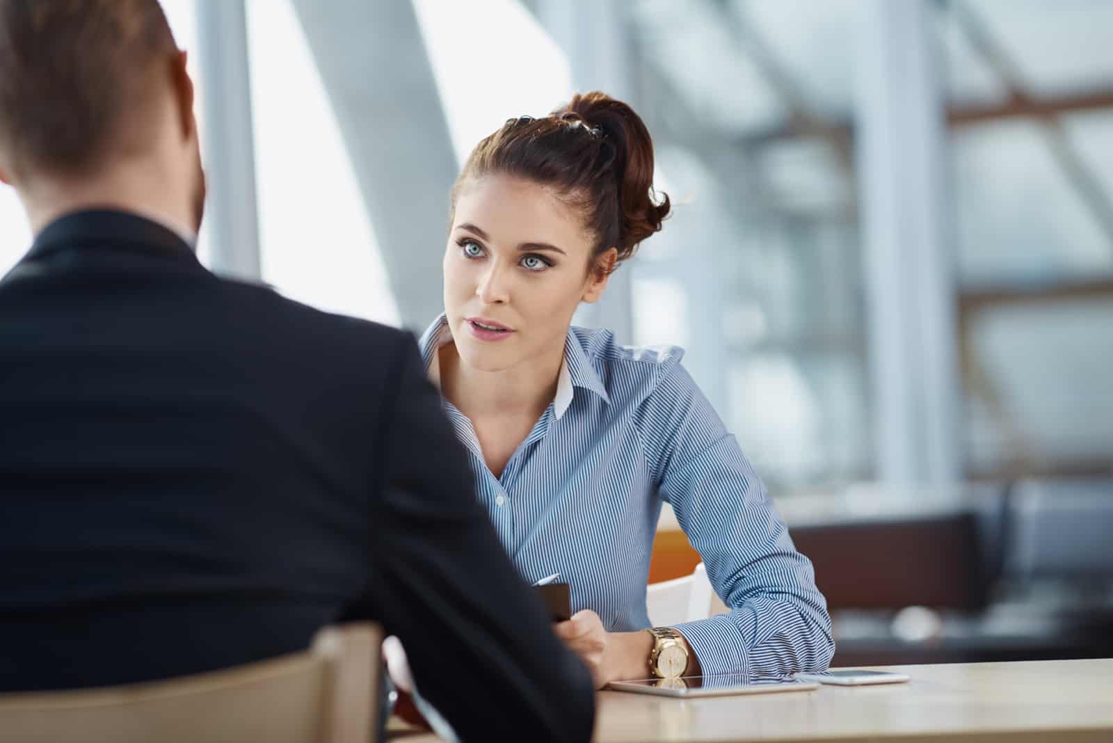 a man and a woman sit at a table and talk