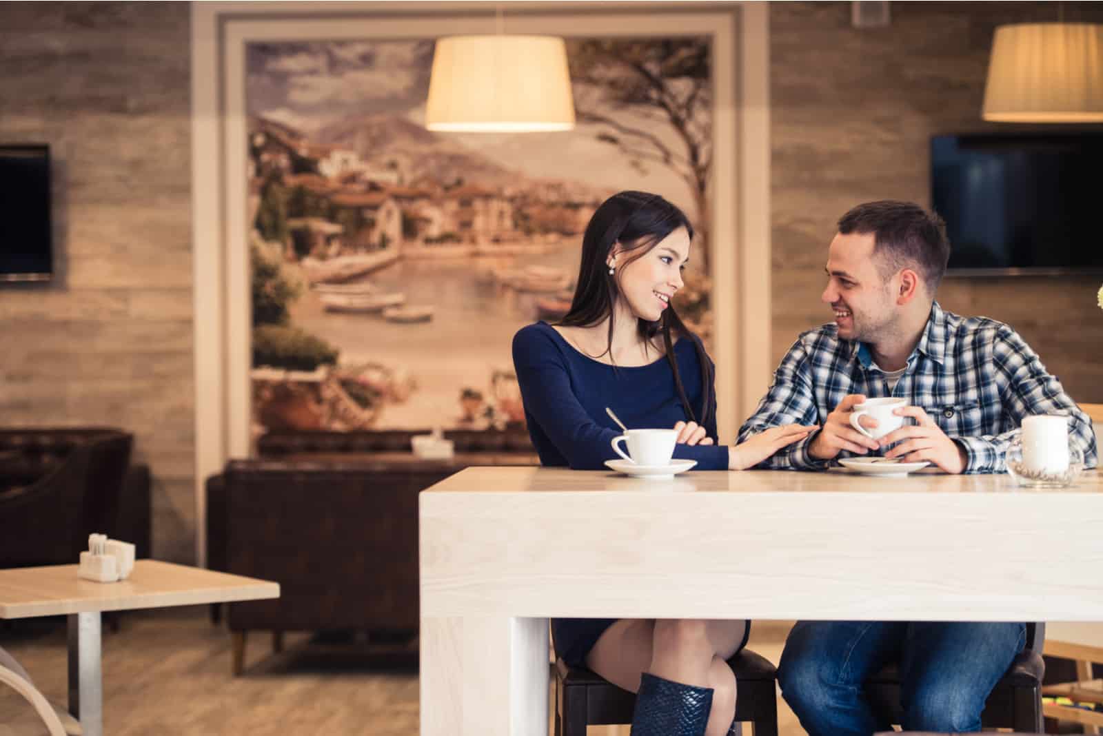 a man and a woman sit in a cafe and talk