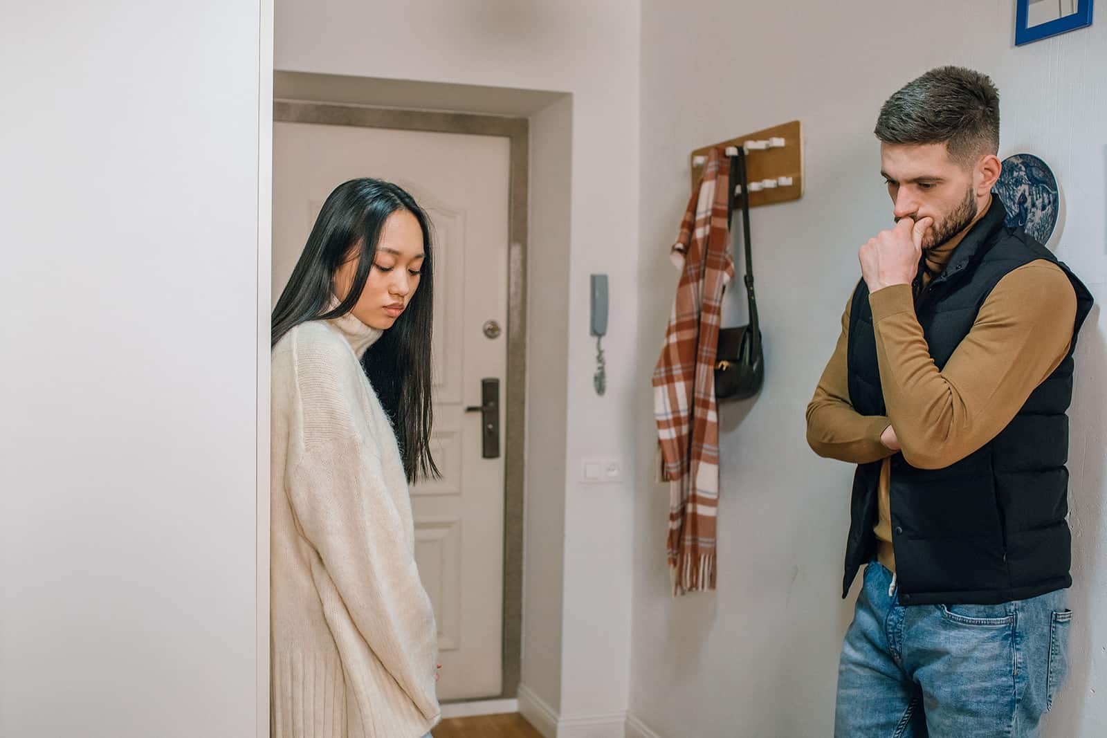 un uomo e una donna in piedi vicino alla porta di un appartamento in un silenzio imbarazzante