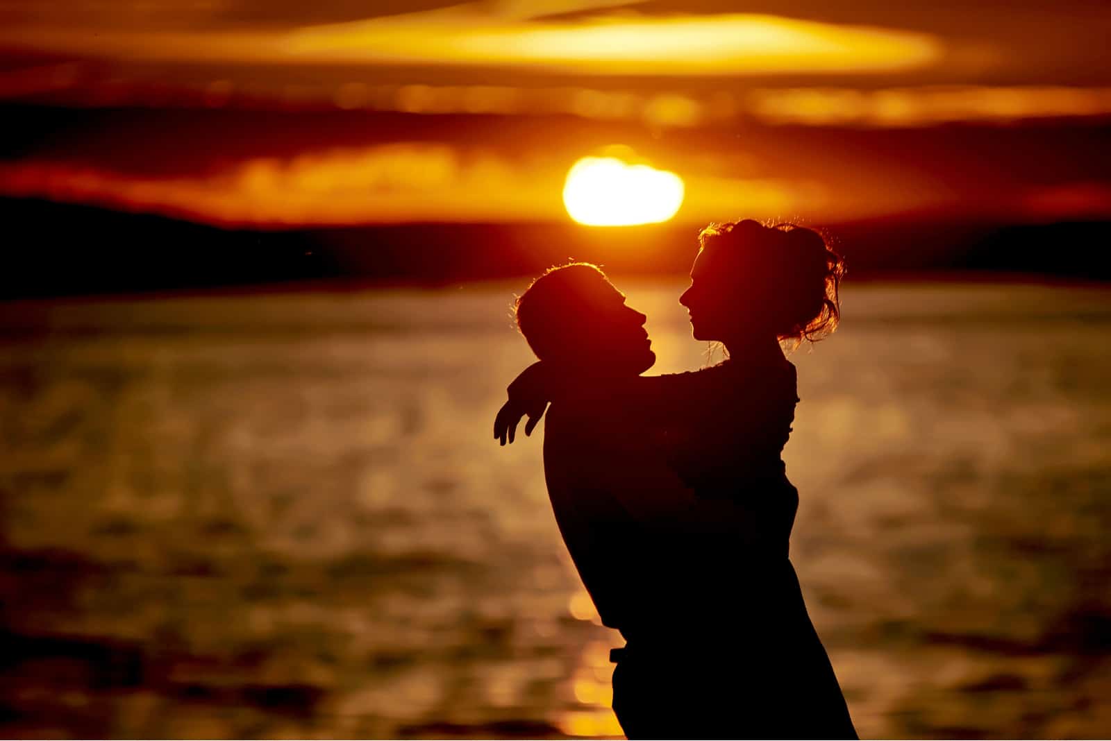 una pareja romántica en la playa abrazándose al atardecer