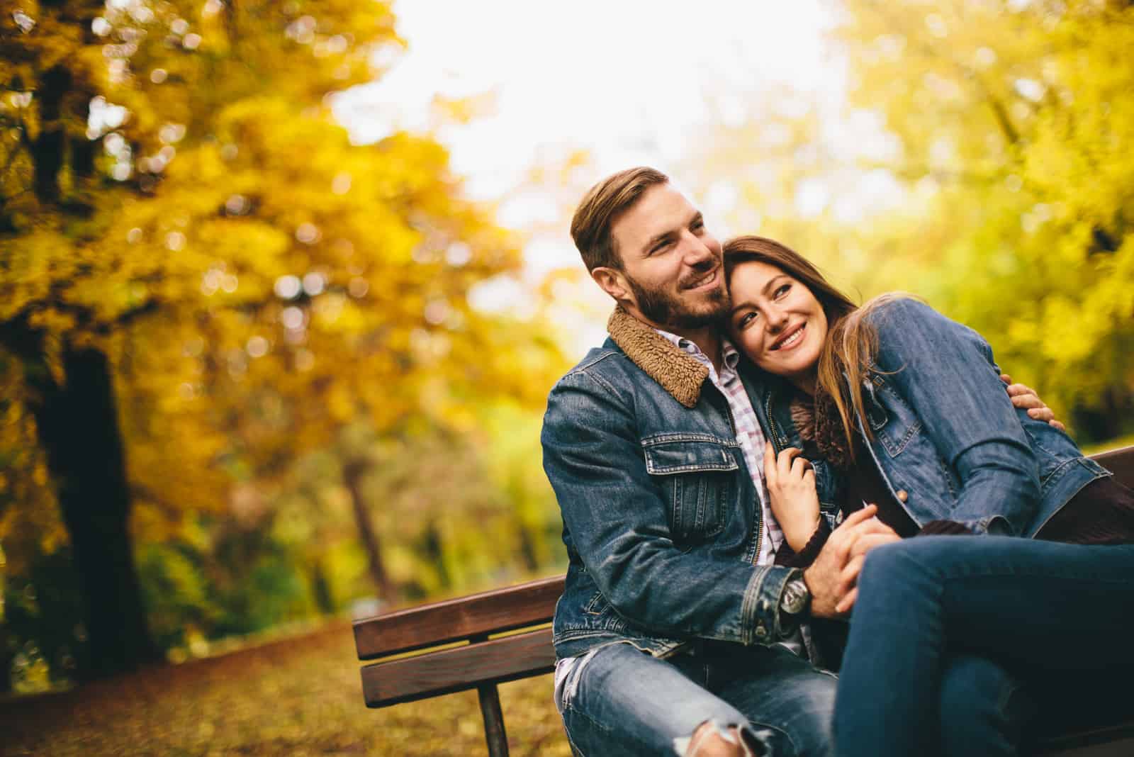 um casal romântico sentado num banco de jardim e abraçado