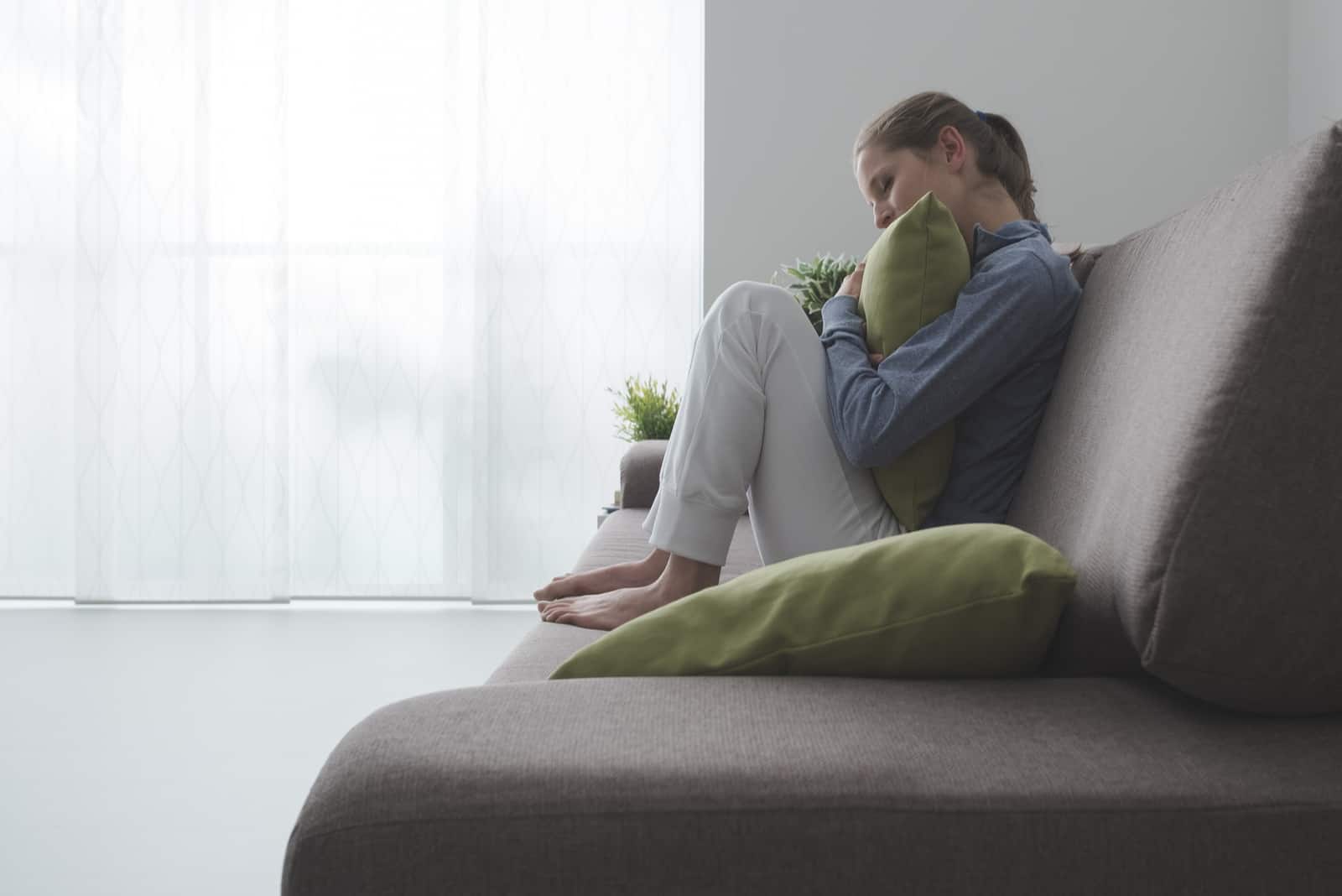 a sad depressed woman sits curled up on the sofa