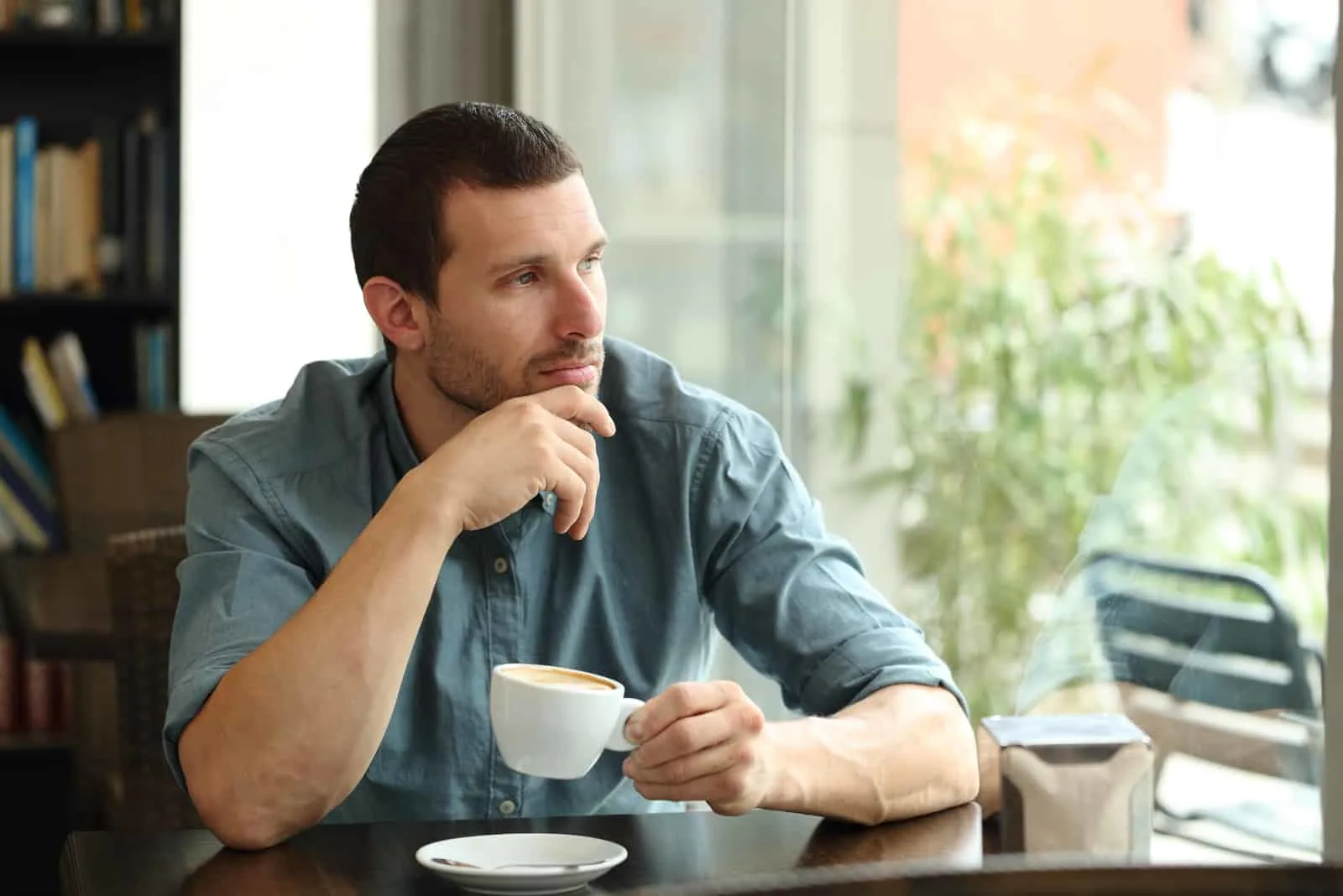 a sad man sitting in a cafe drinking coffee