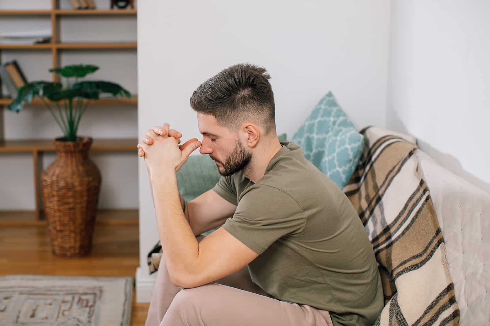 a sad man sitting on the couch leaning head on hands