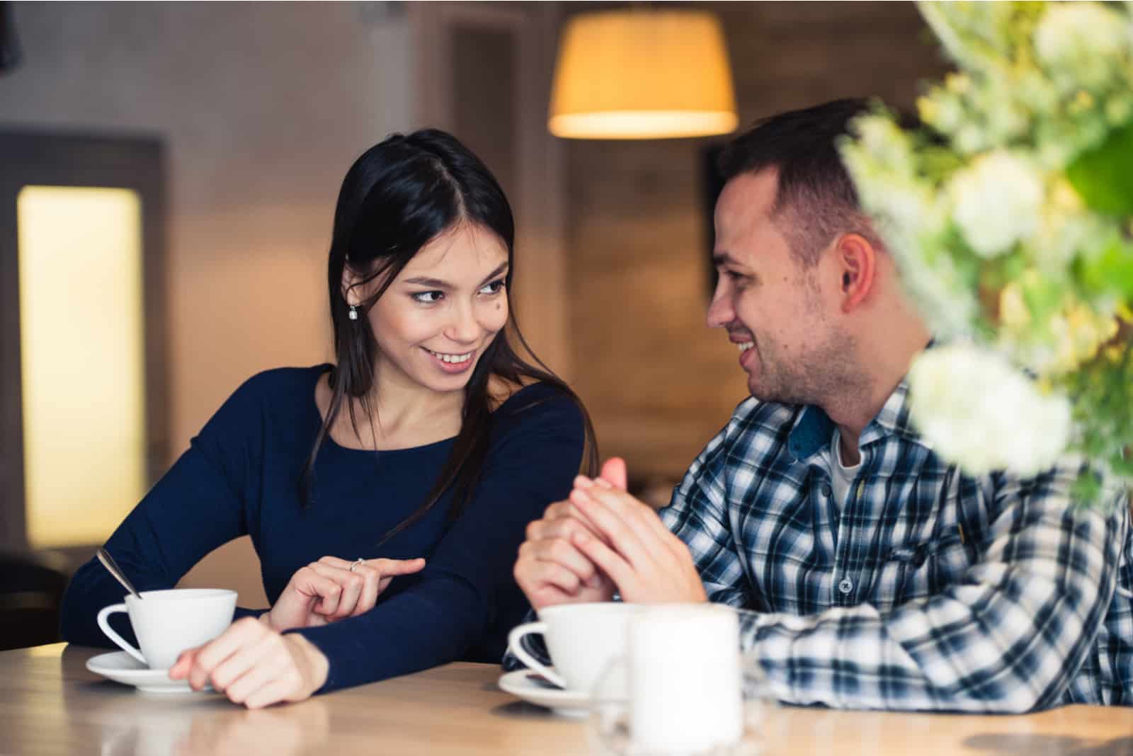 a smiling couple at the bar drinking coffee and talking