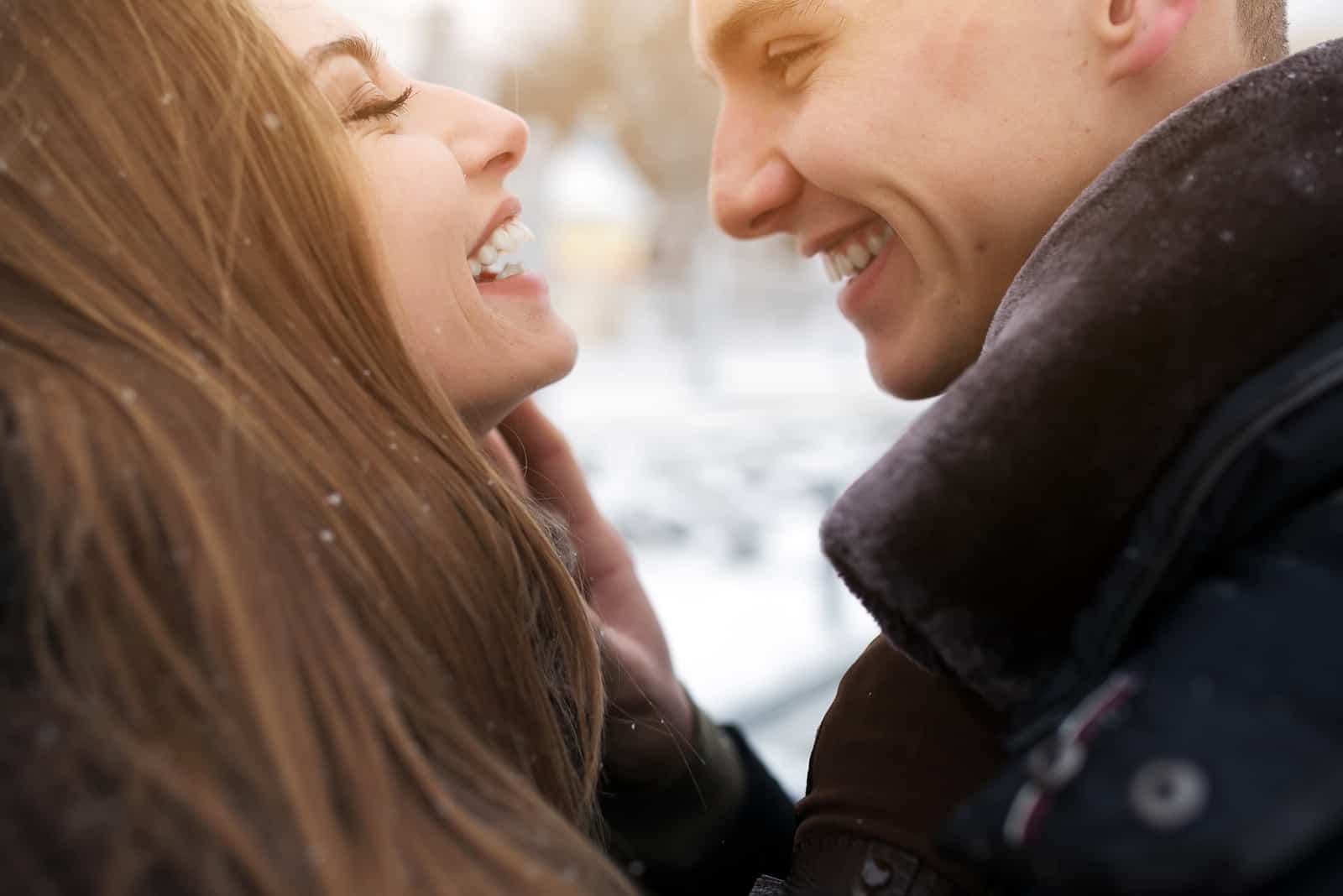 una coppia sorridente fuori nella neve che si abbraccia