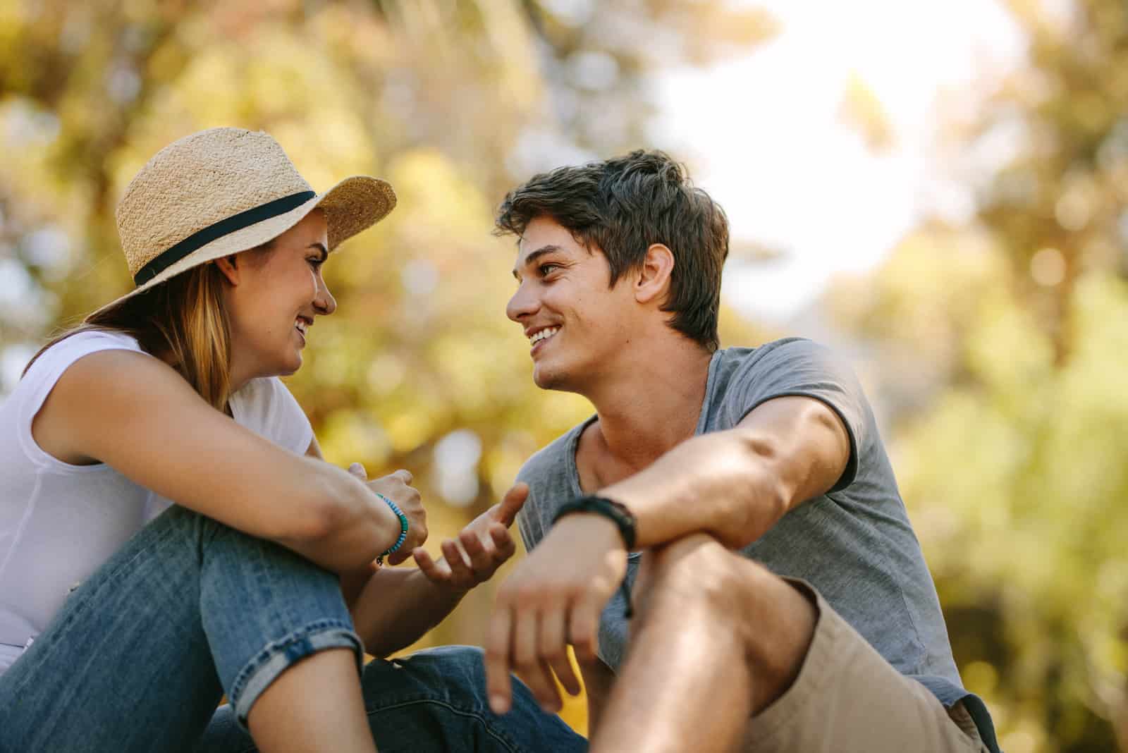 a smiling couple sitting in nature and talking