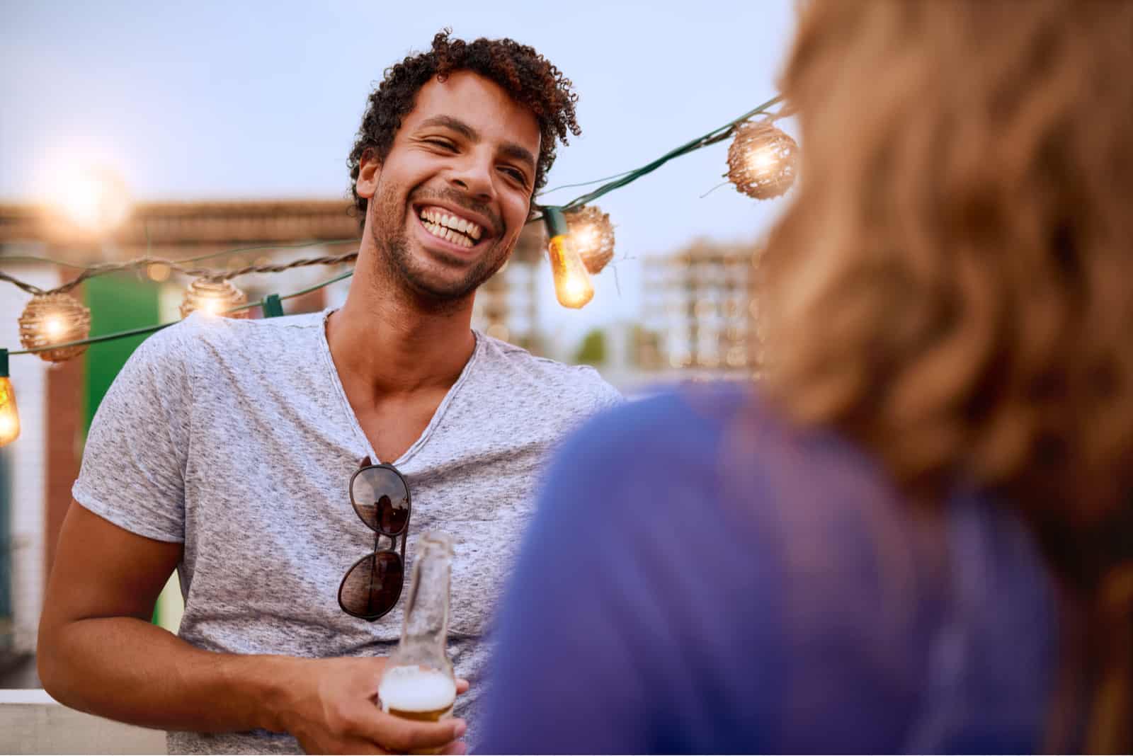 un uomo sorridente con una birra in mano flirta con una donna