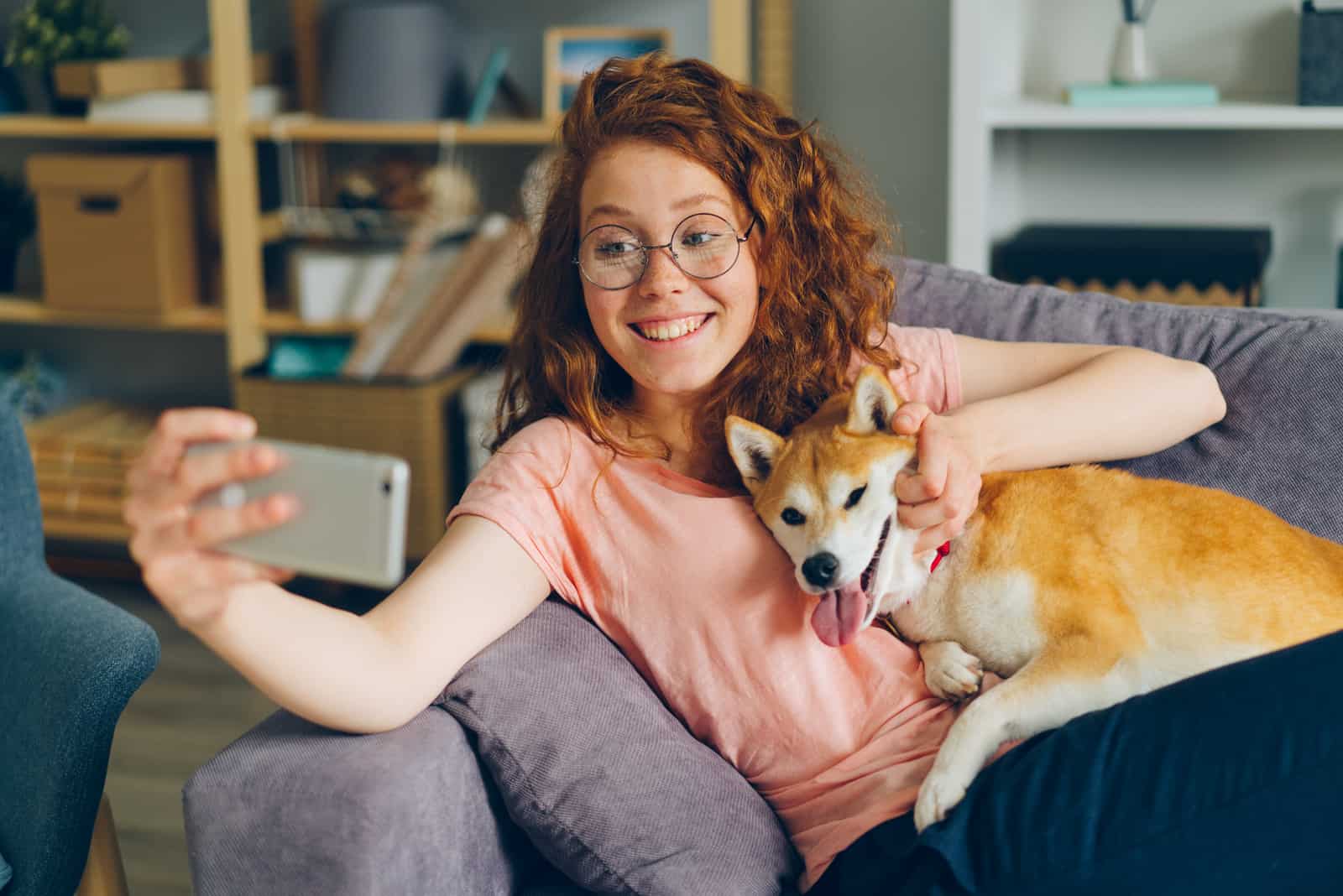 a smiling woman takes a picture with a dog