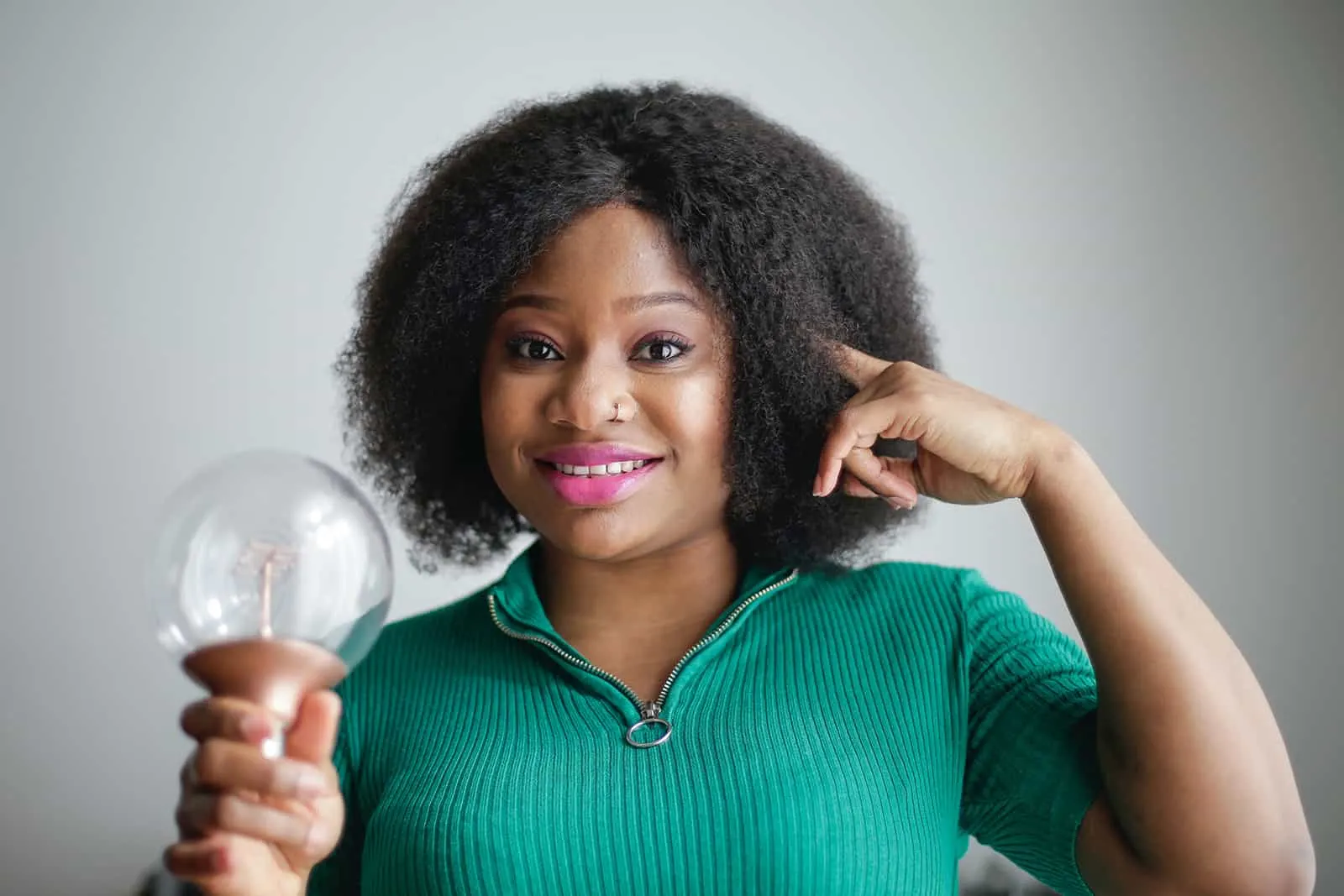 a woman holding a light bulb and touching head with finger