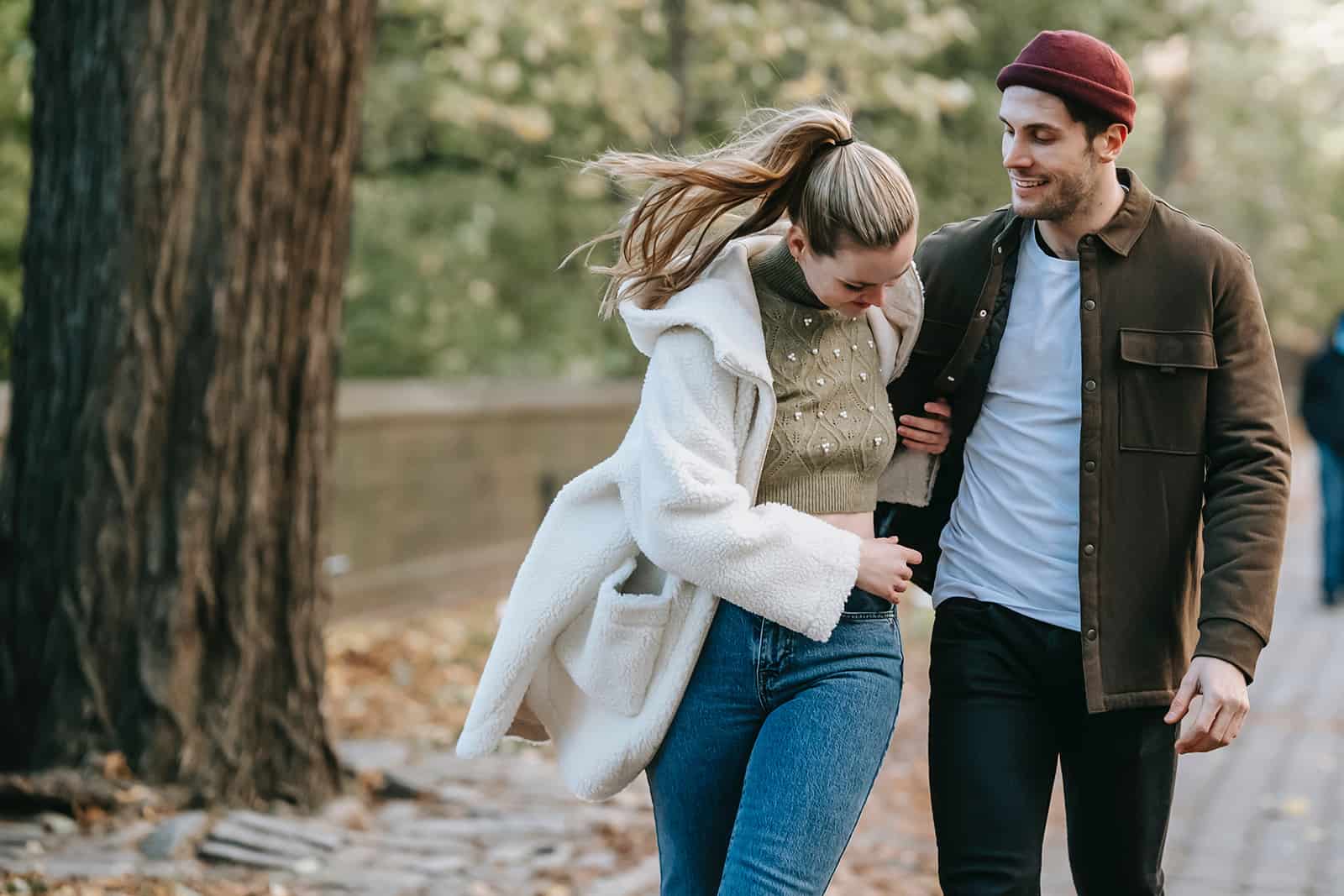 una donna che tiene la mano di un uomo mentre camminano insieme nel parco
