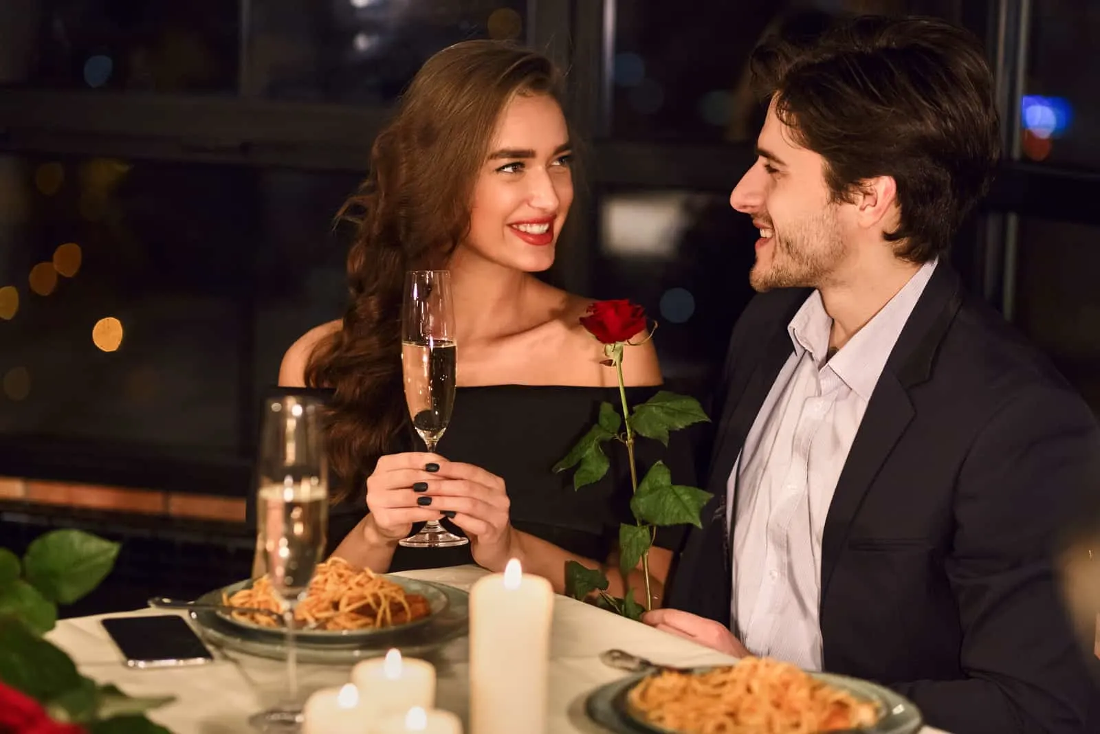 at dinner with wine a man gives a rose to an overjoyed woman