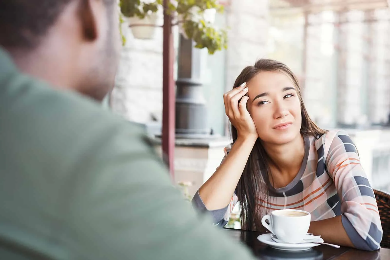 confused woman looking at man sitting with her in a cafe on a date