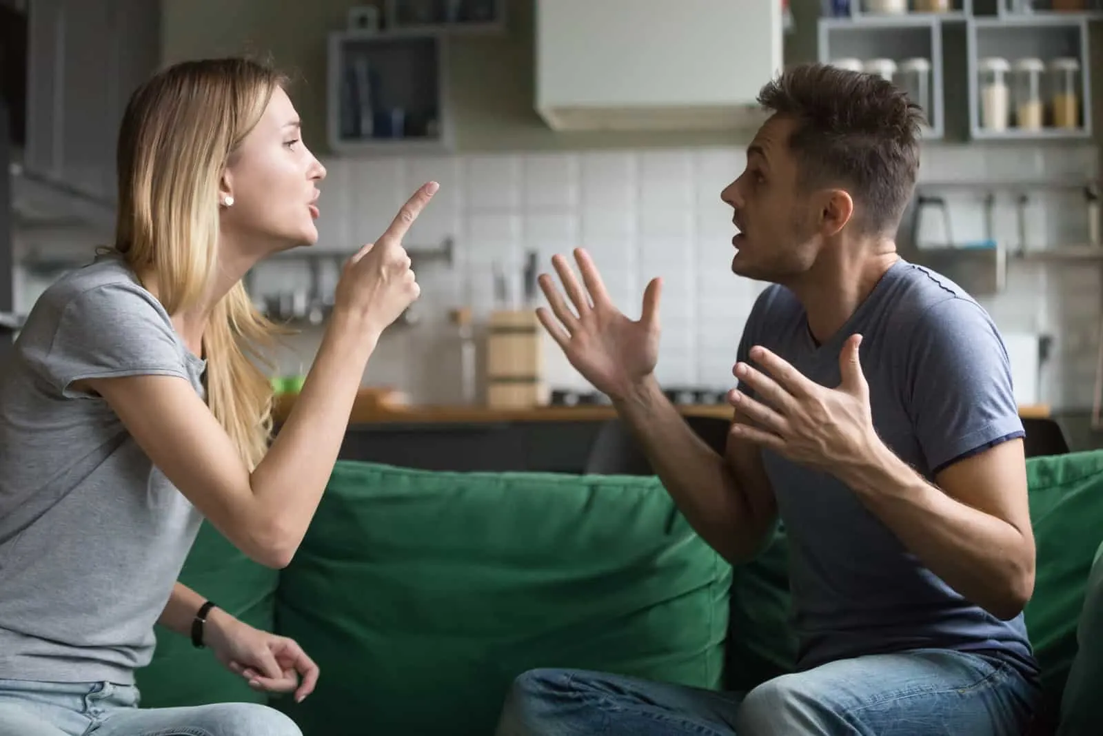 man and woman arguing while sitting on sofa 
