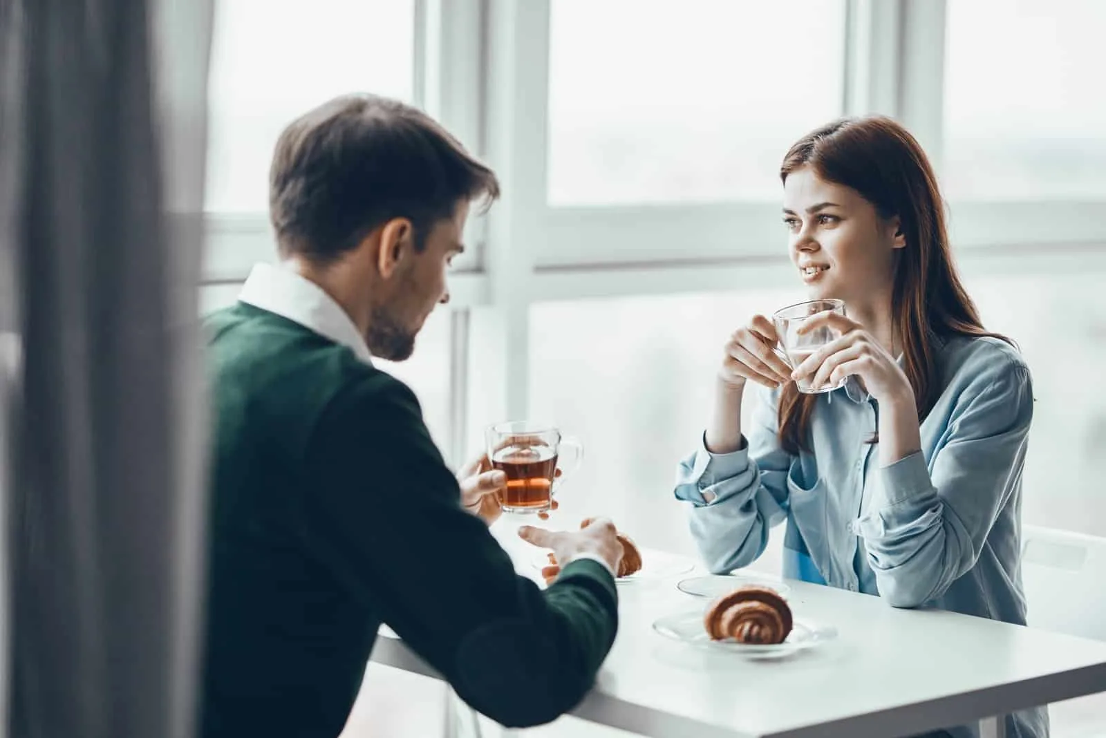 man and woman drinking tea while sitting in cafe