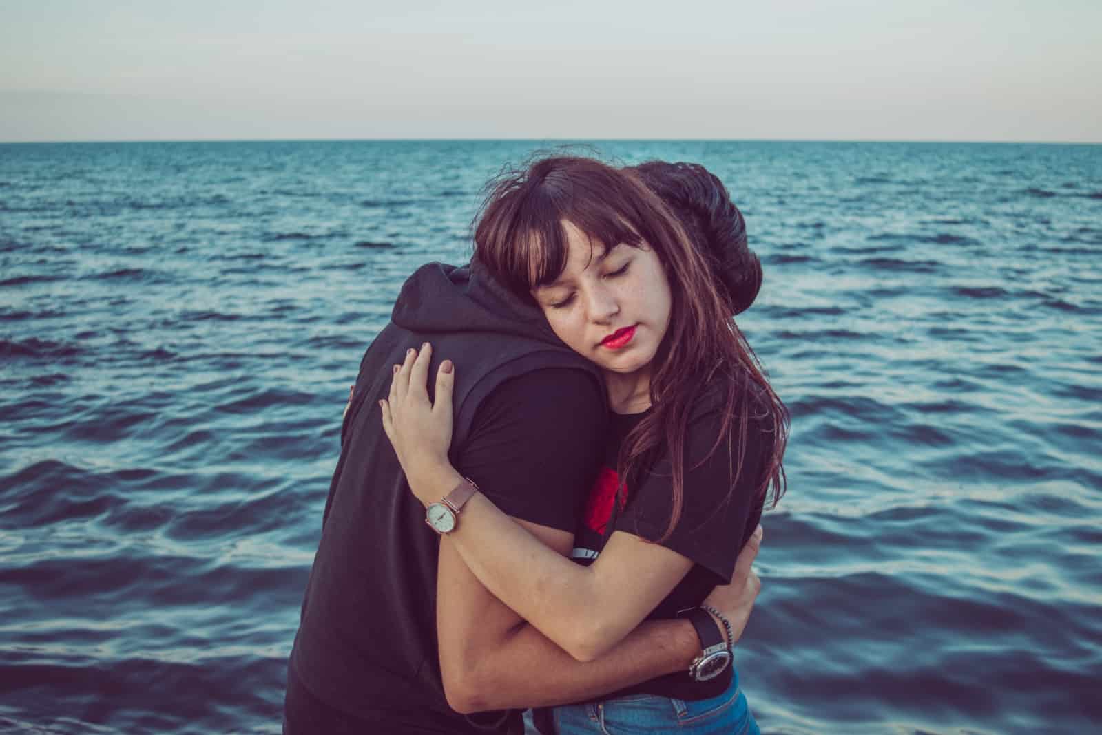 uomo e donna che si abbracciano vicino al mare