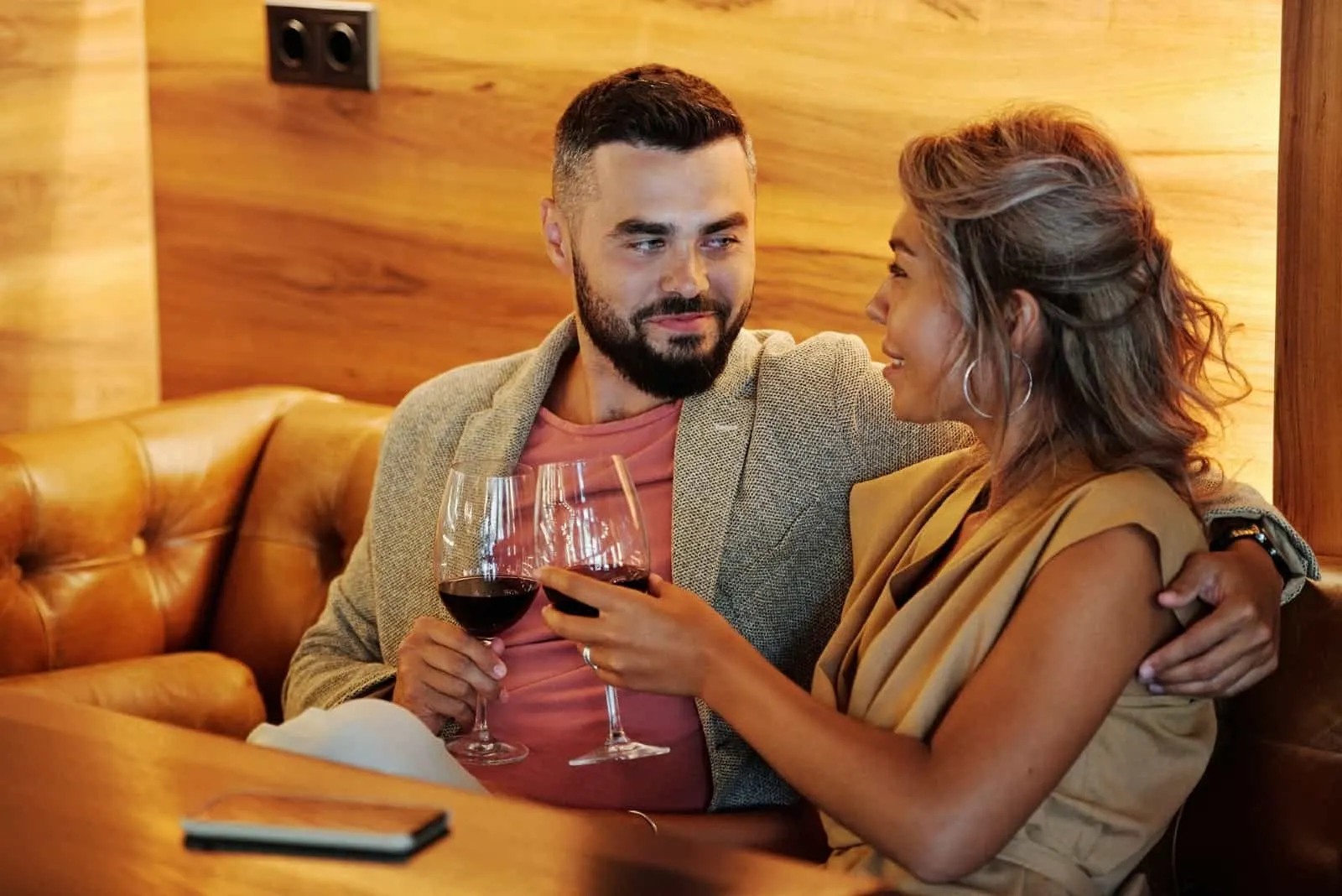 man and woman making eye contact while holding wine glasses