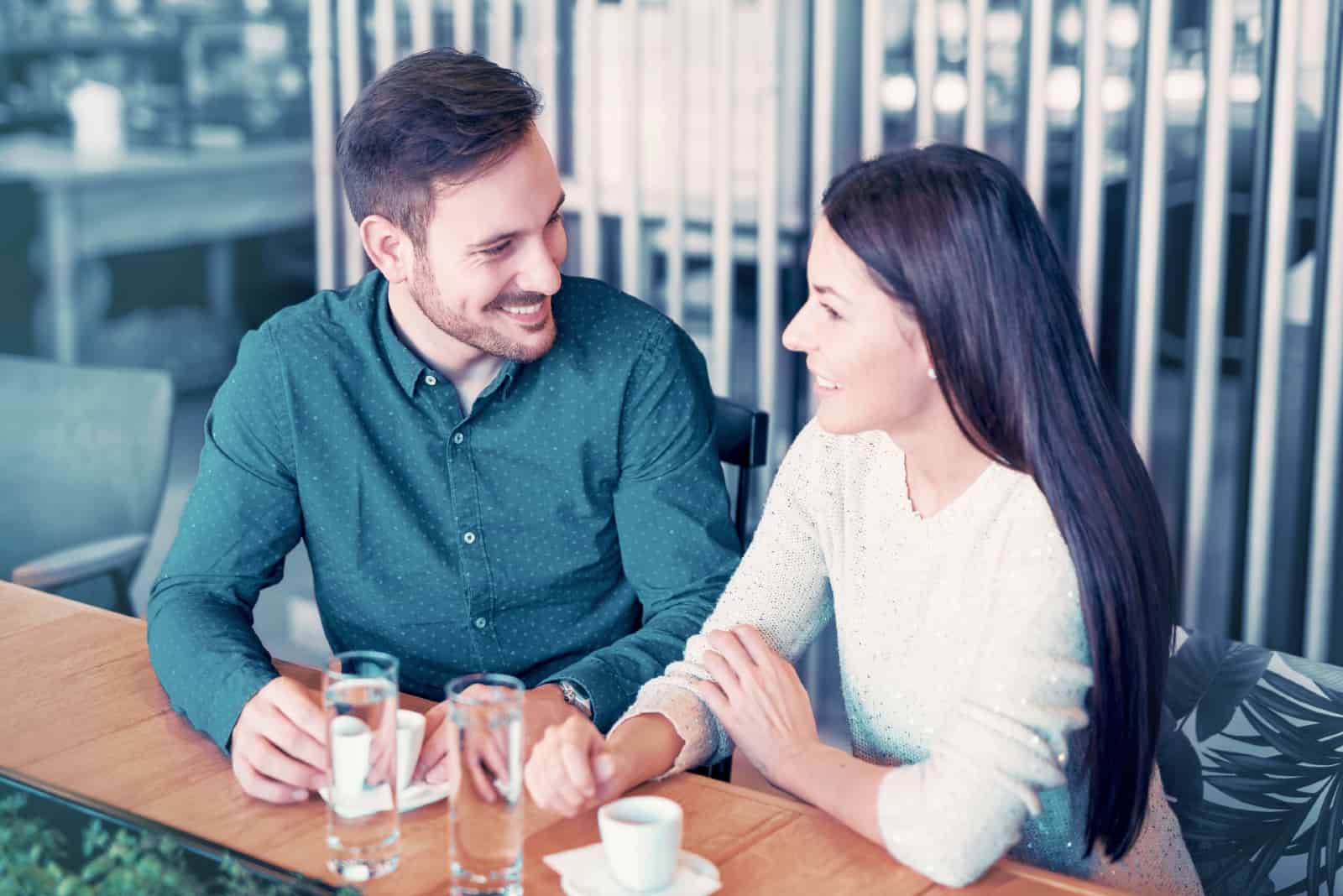 man and woman having coffee while sitting in cafe