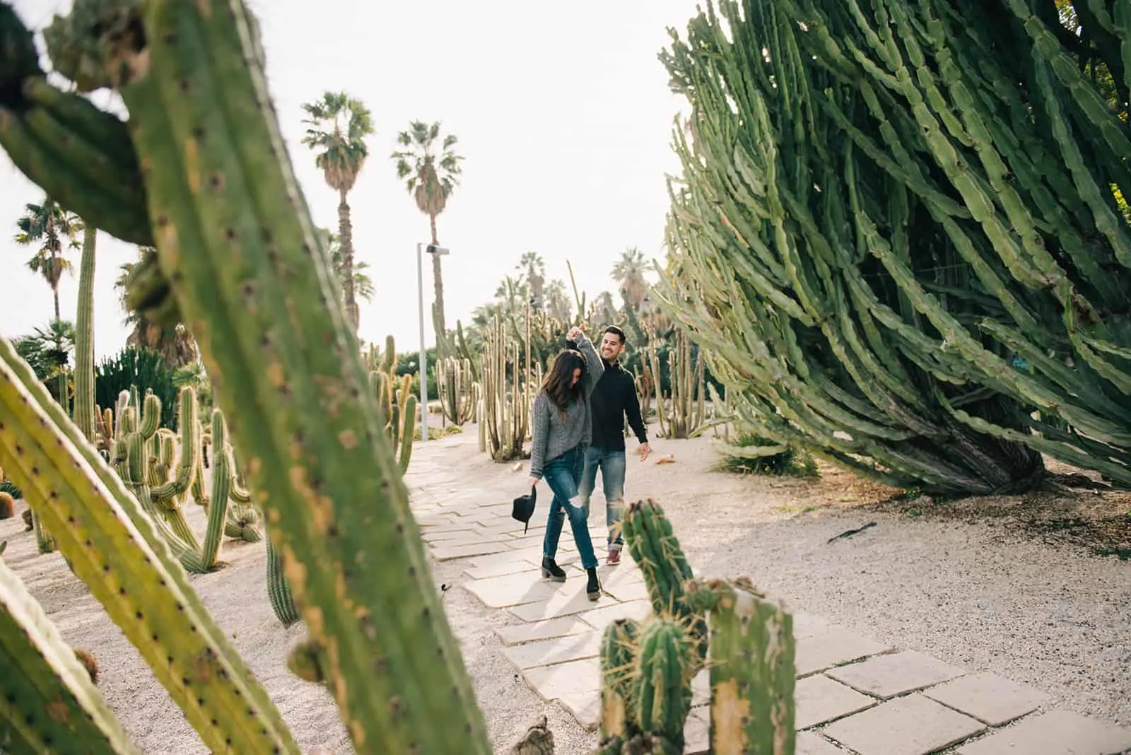 happy couple dancing among the cactus plants during daytime