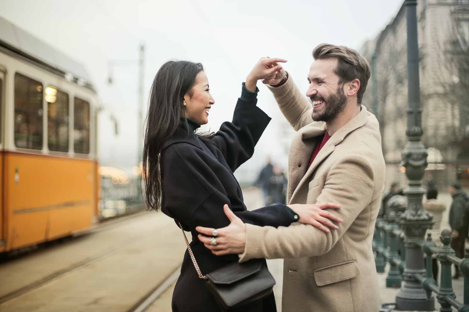 happy couple dancing on a sidewalk and looking at each other