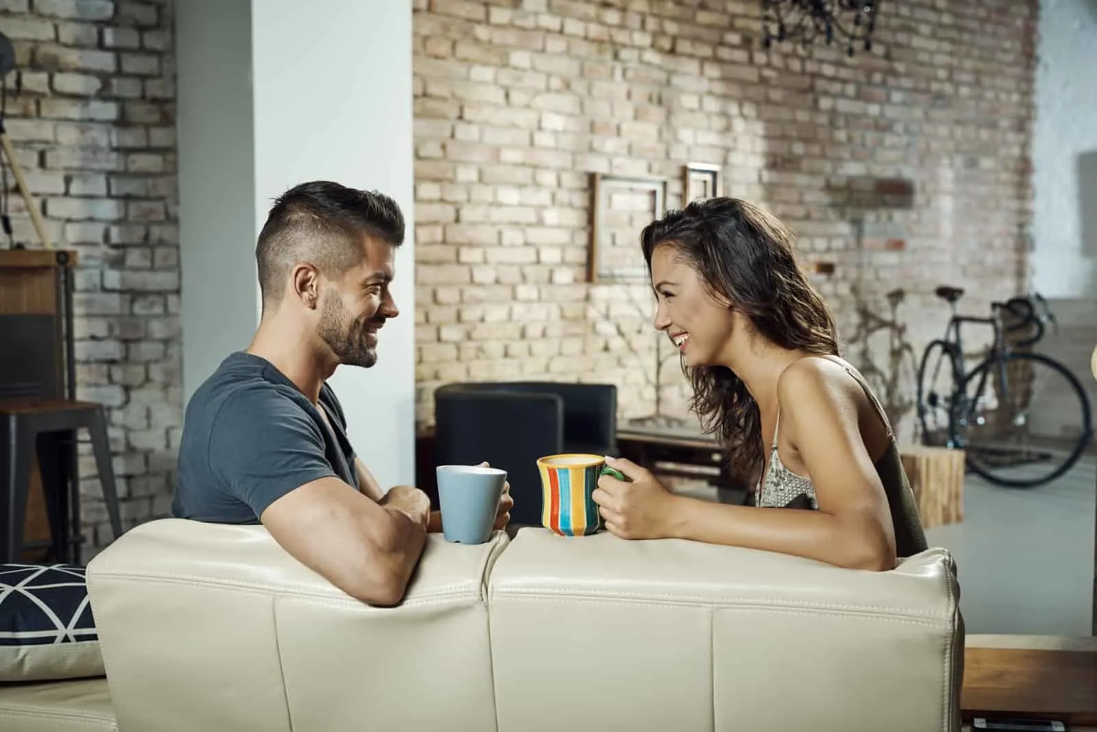 happy couple sitting on sofa drinking coffee and talking