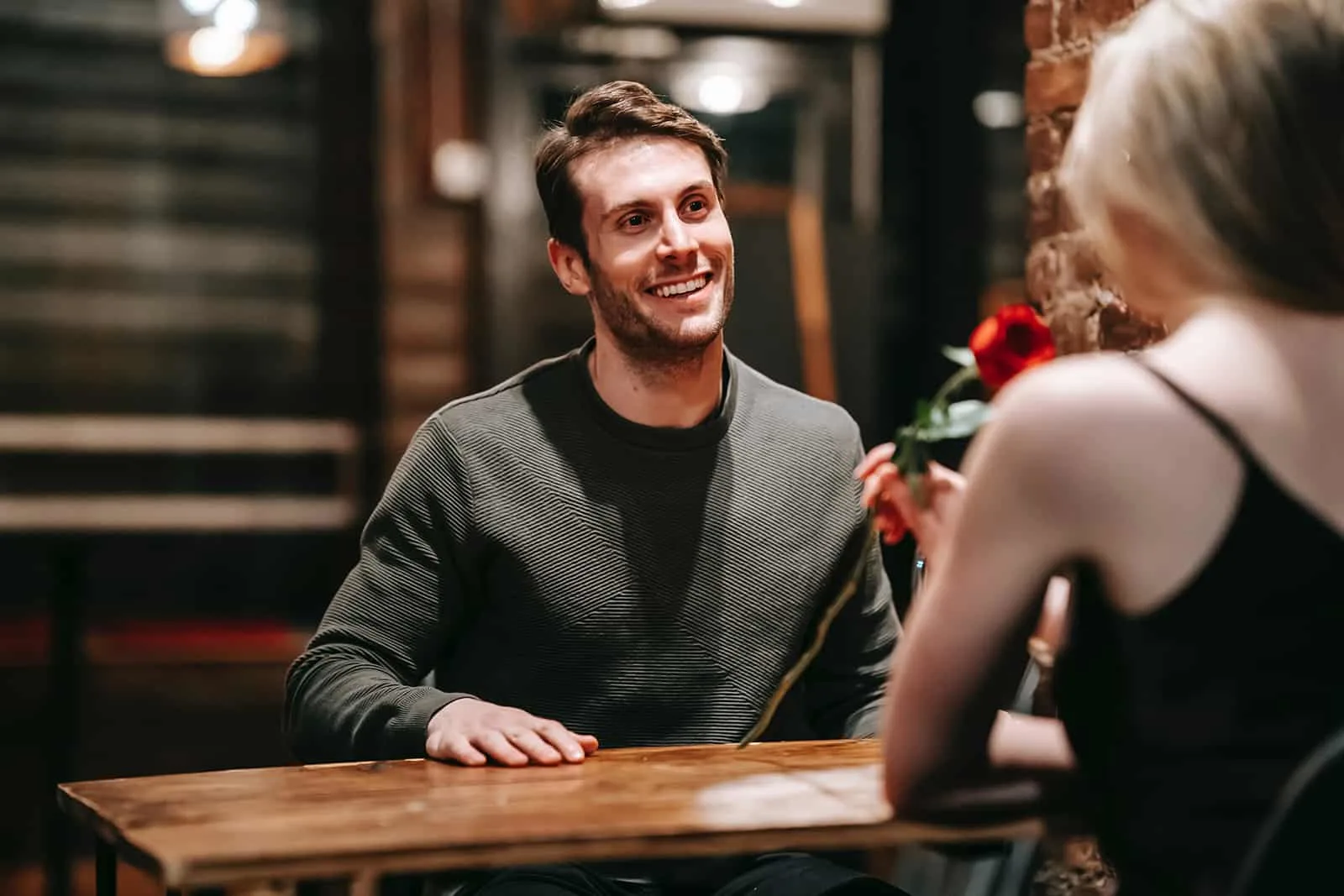 happy man looking at his girlfriend smelling a red rose