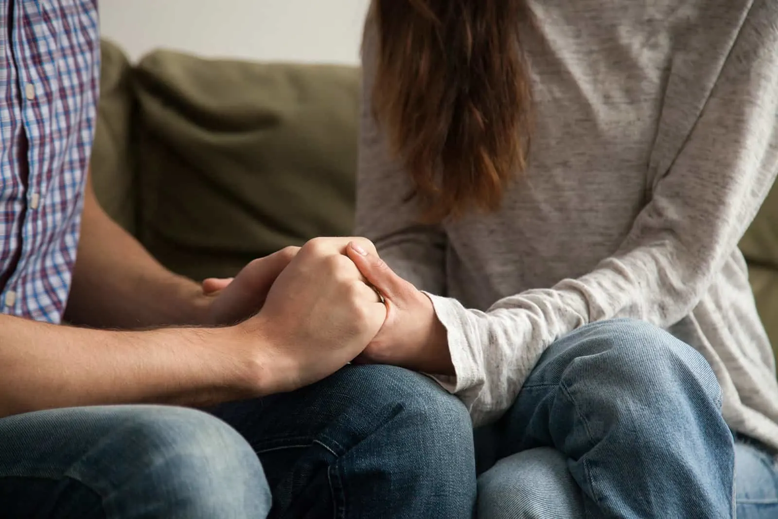 man and woman holding hands while sitting on the sofa together