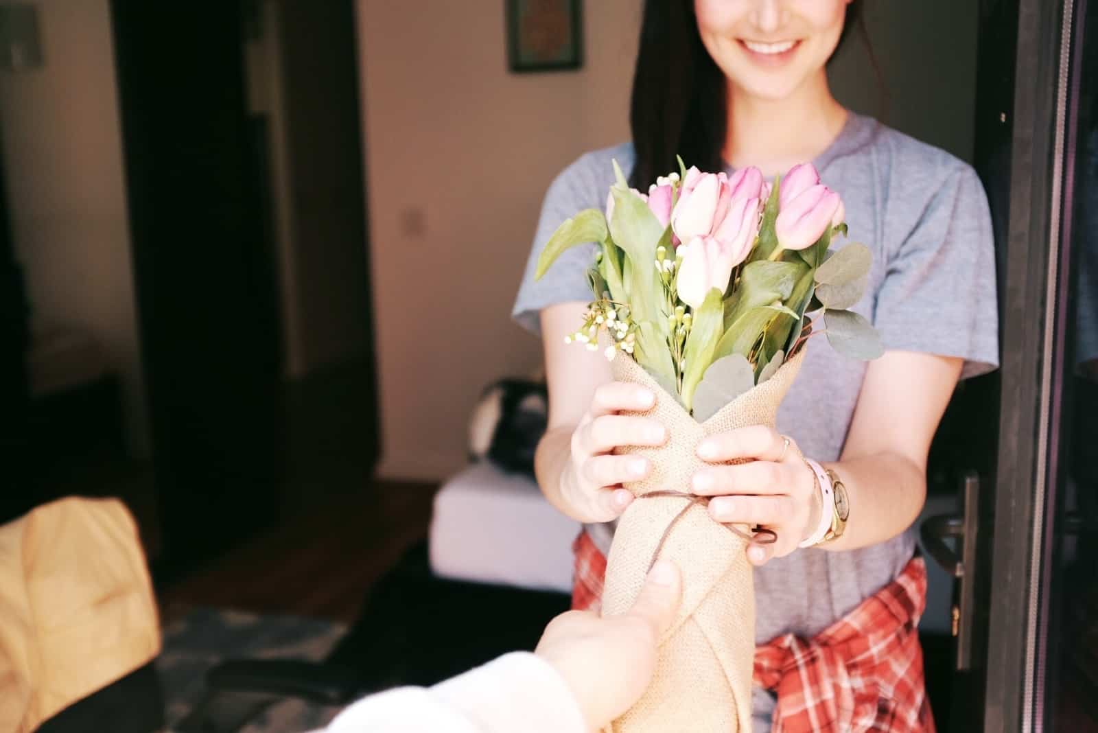 man giving bouquet of flowers to woman in gray t-shirt