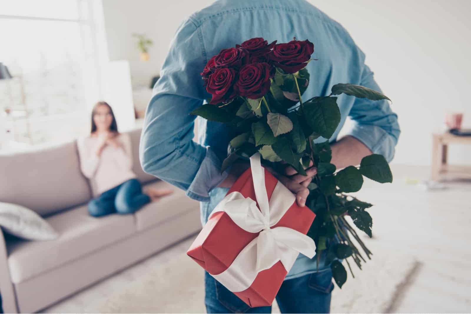 man holding gift and red roses while looking at woman