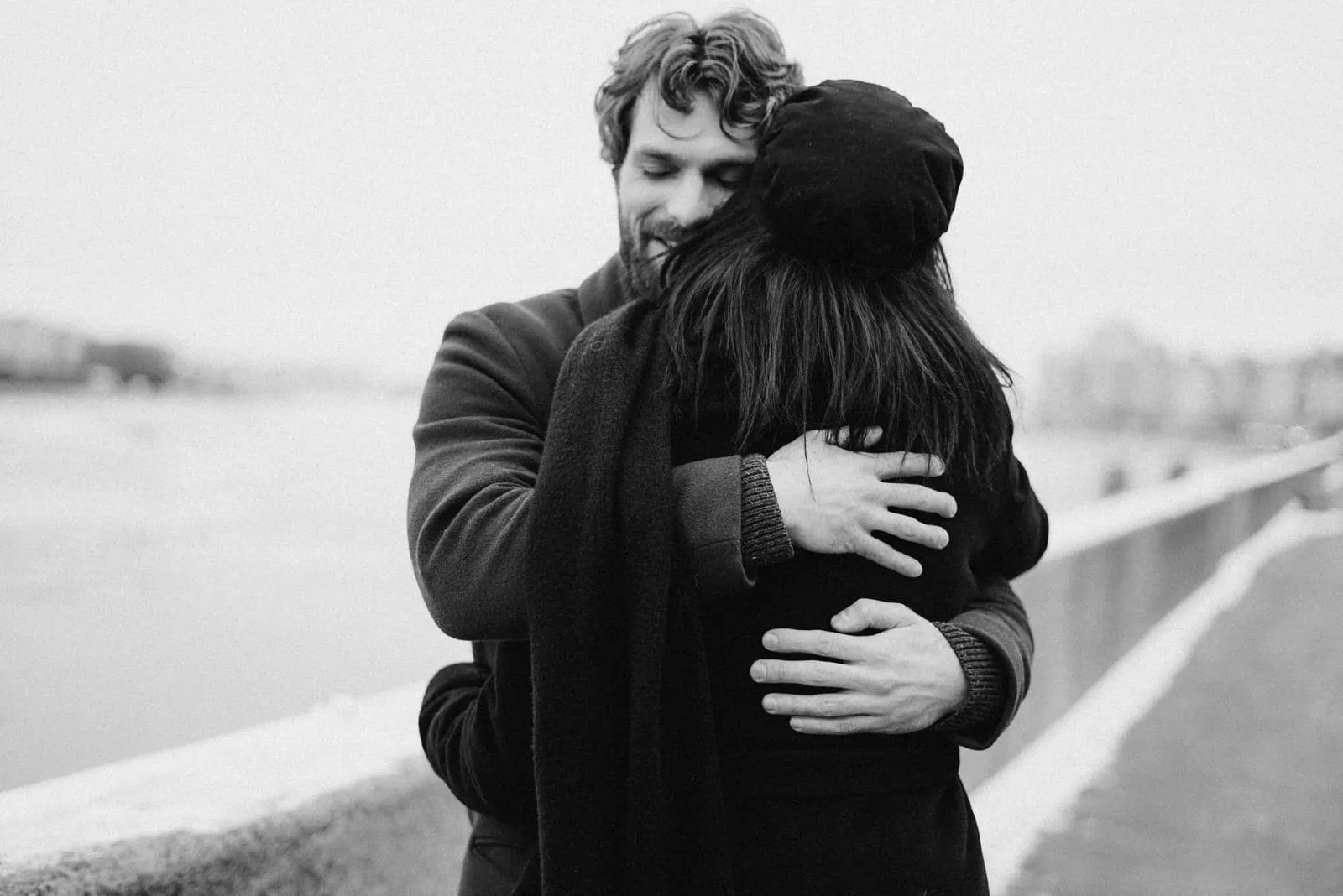 happy man hugging woman while standing near water