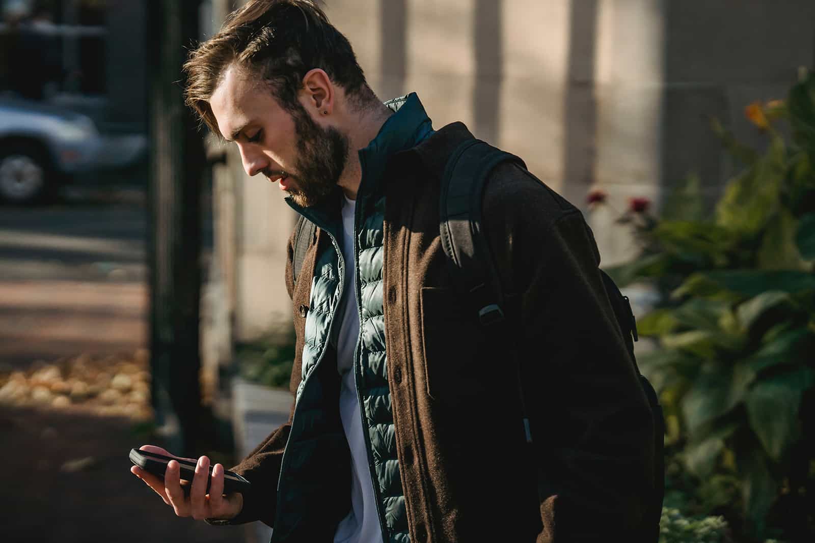 hombre mirando el smartphone mientras está de pie al aire libre solo