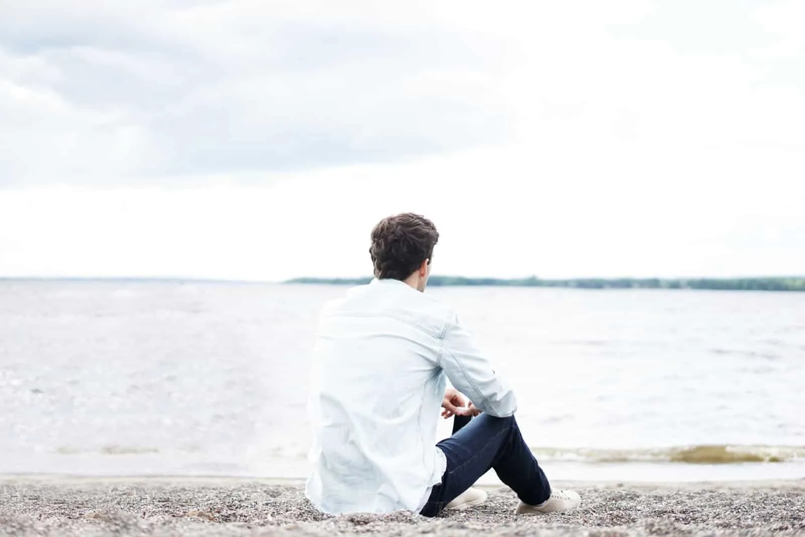 man in white shirt sitting near water