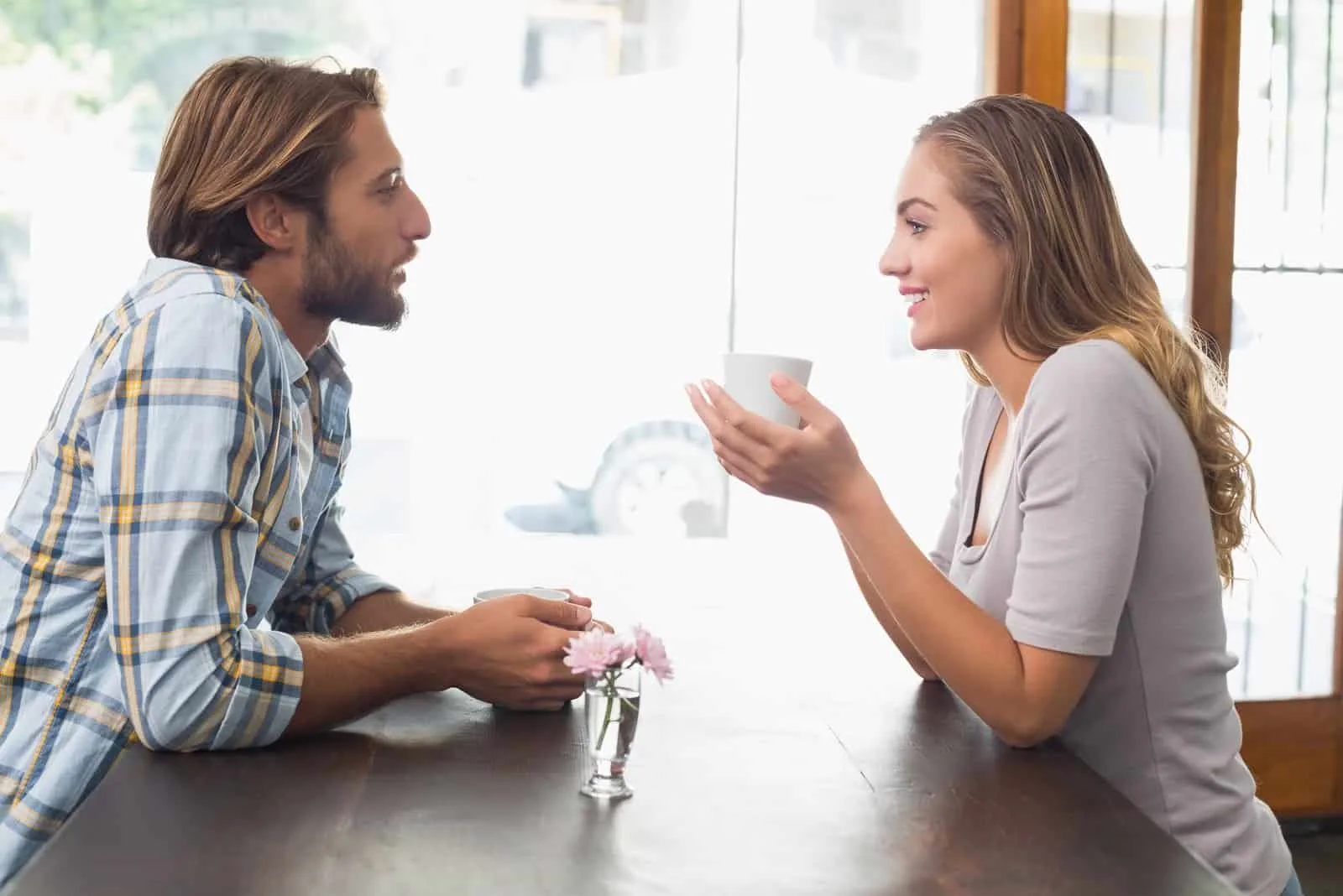 man talking to woman while having coffee in cafe