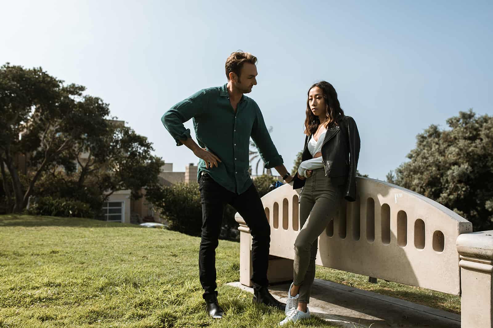 man talking with upset woman leaning on the bench in the park