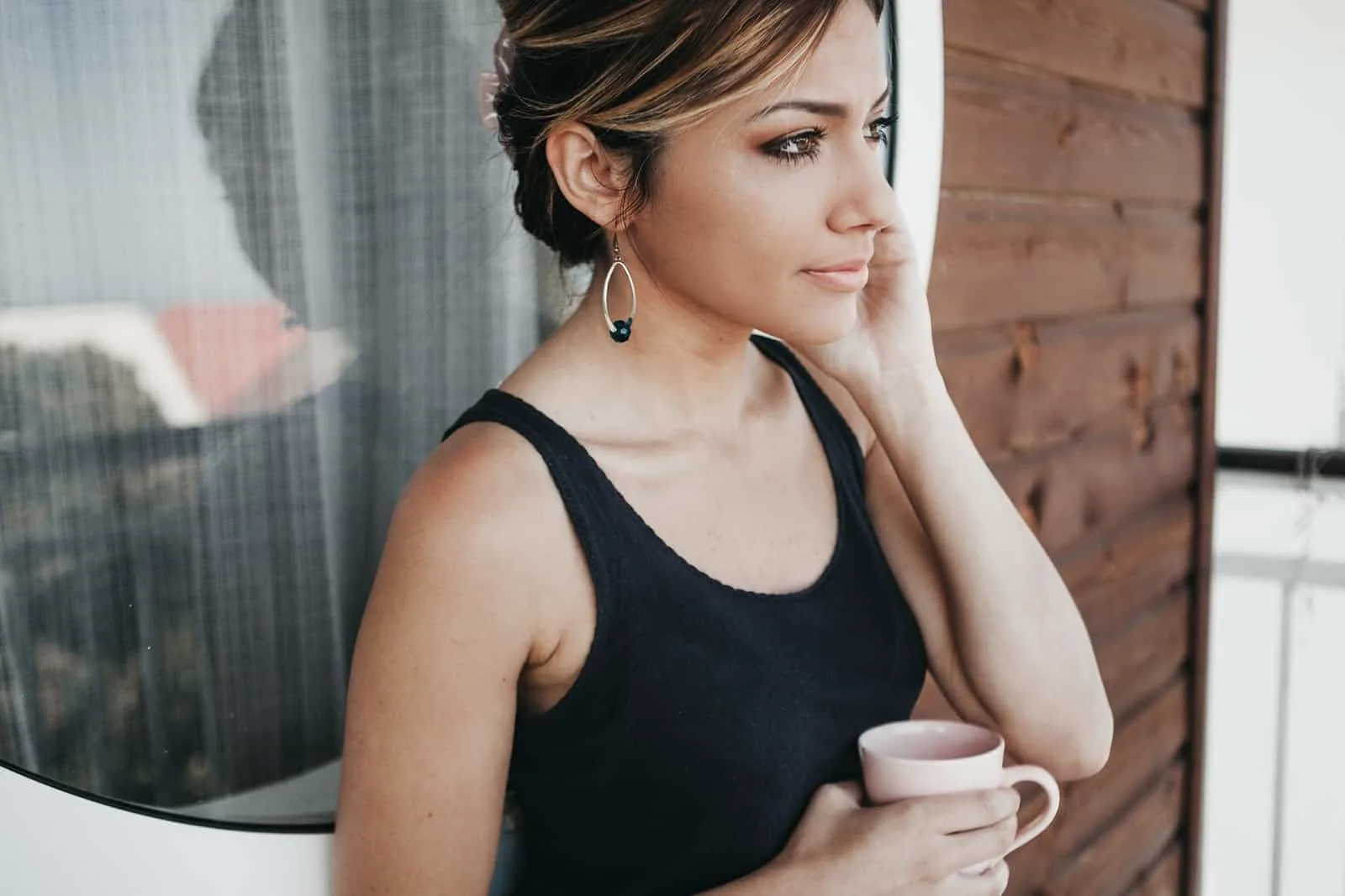 pensive woman holding coffee standing on the terrace