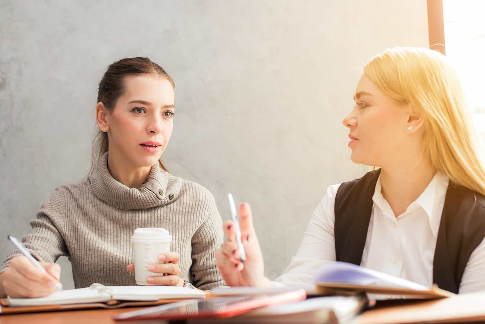 pensive woman listening to female colleague while working together