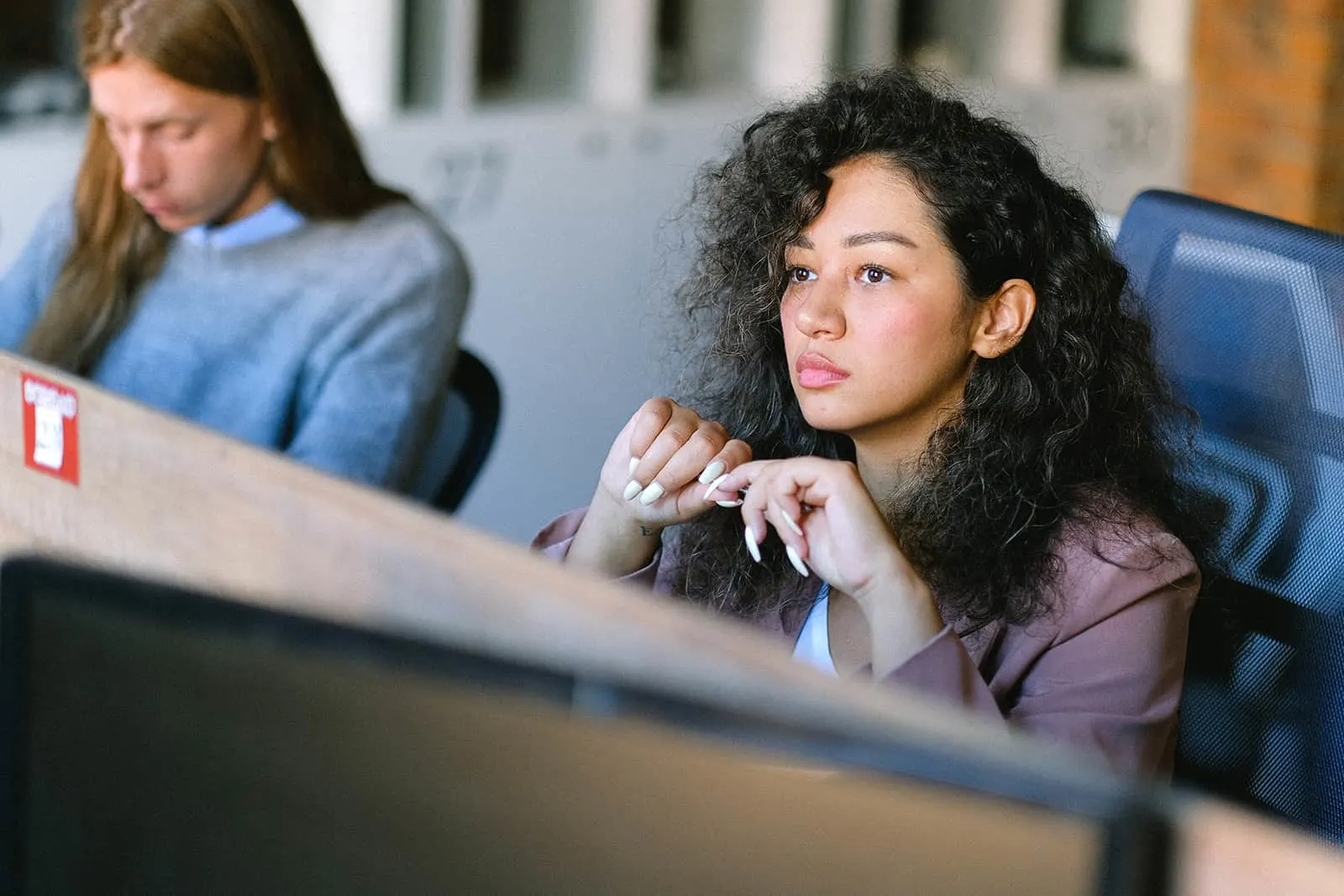 pensive woman sitting at workplace and looking straight in front her
