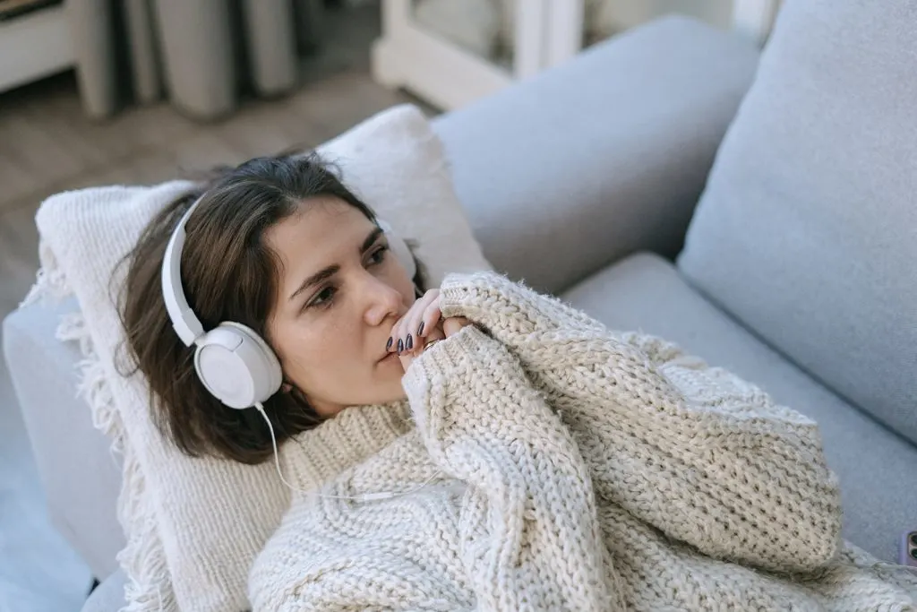 sad woman listening to a music while lying on the sofa